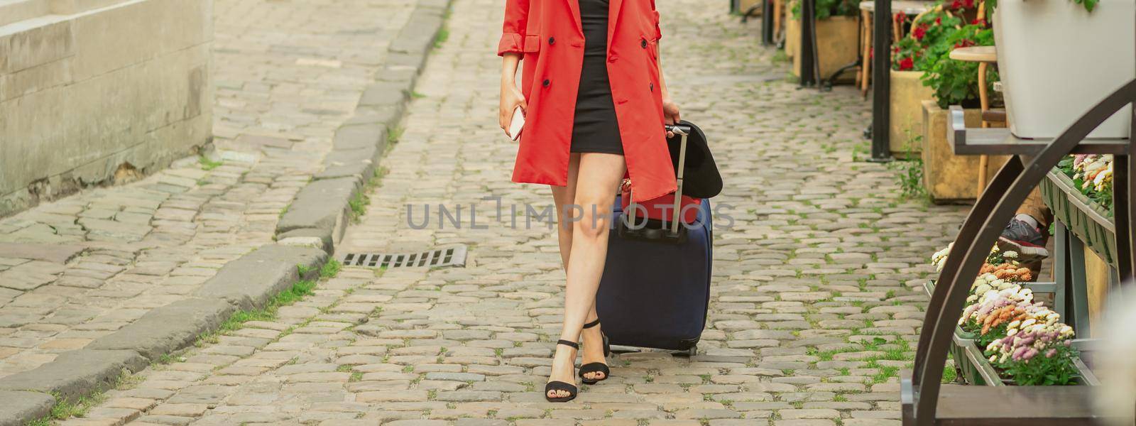 Beautiful young business woman walking on the tram track of a city street with blue travel bag.