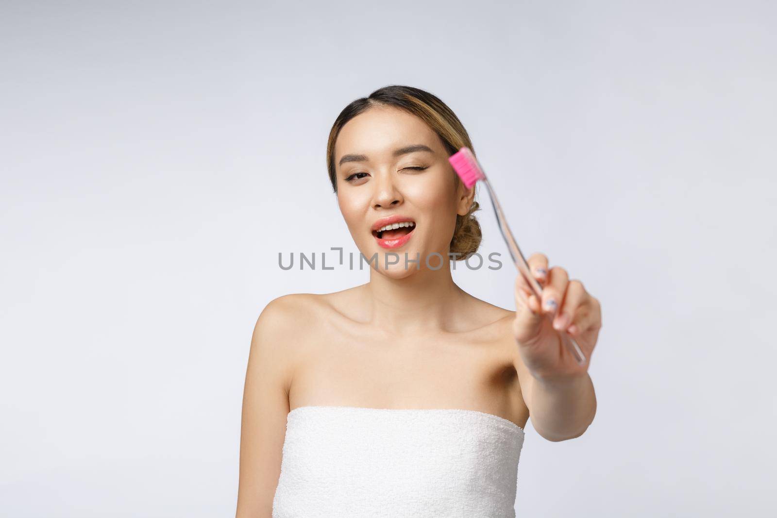 Beautiful young woman on white isolated background holds a toothbrush, Asian.