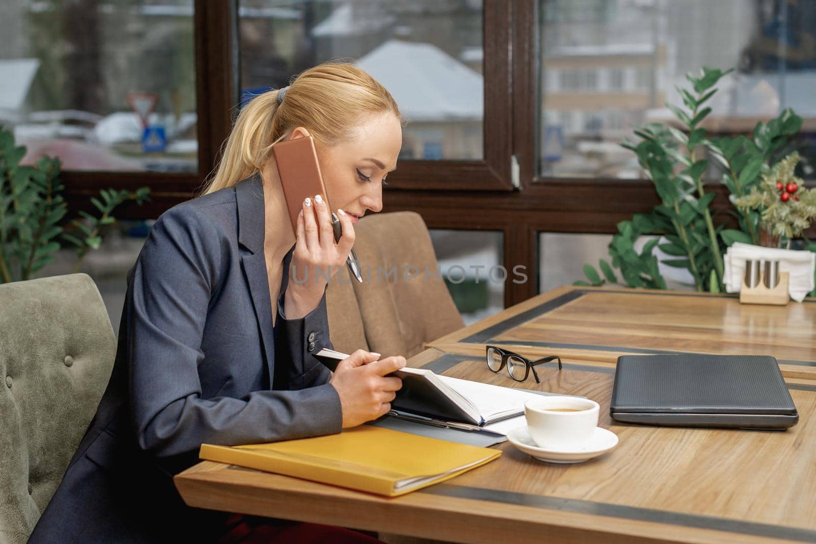 Young business woman is having phone call sitting at the table in the home office.