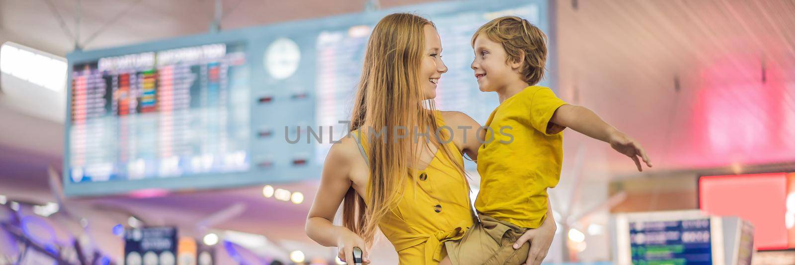 Family at airport before flight. Mother and son waiting to board at departure gate of modern international terminal. Traveling and flying with children. Mom with kid boarding airplane. yellow family look. BANNER, LONG FORMAT