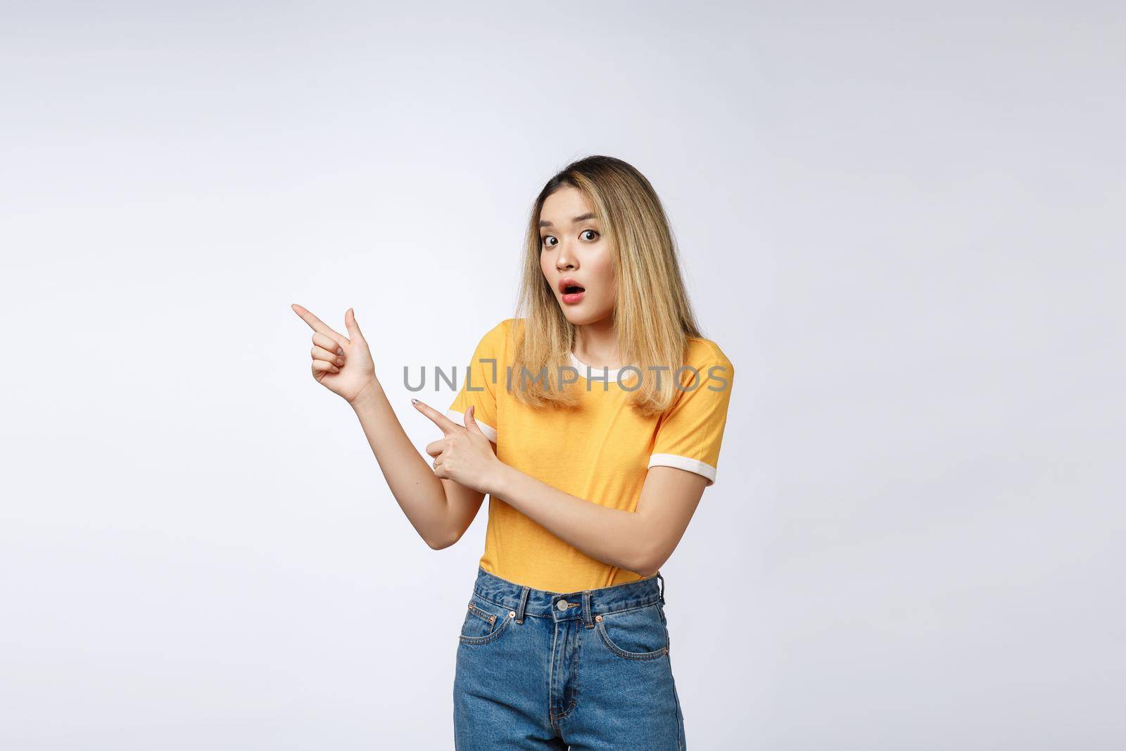 Smiling woman pointing finger on copy space. Isolated portrait on white