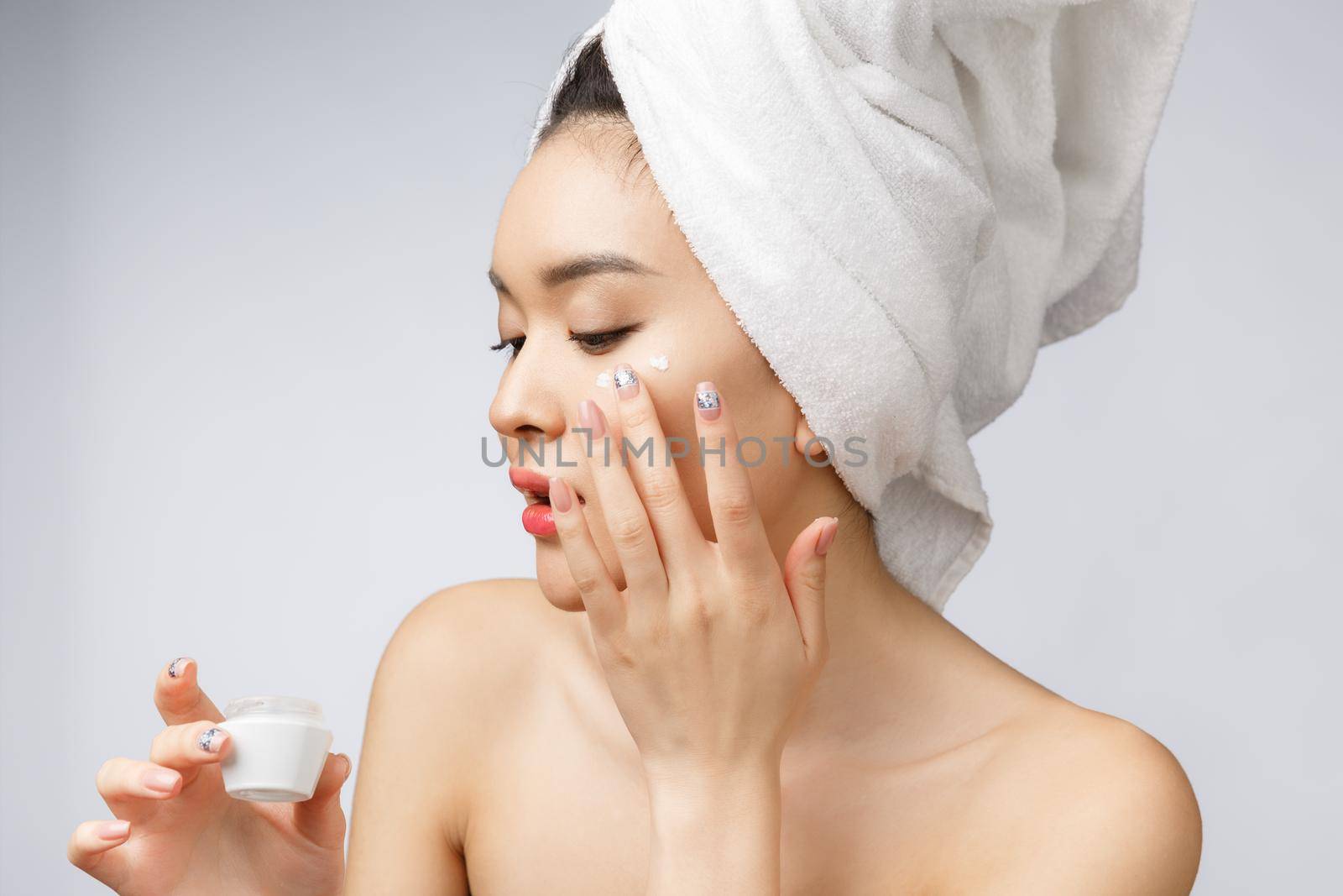 health and beauty concept - Attractive asian woman applying cream on her skin, isolated on white