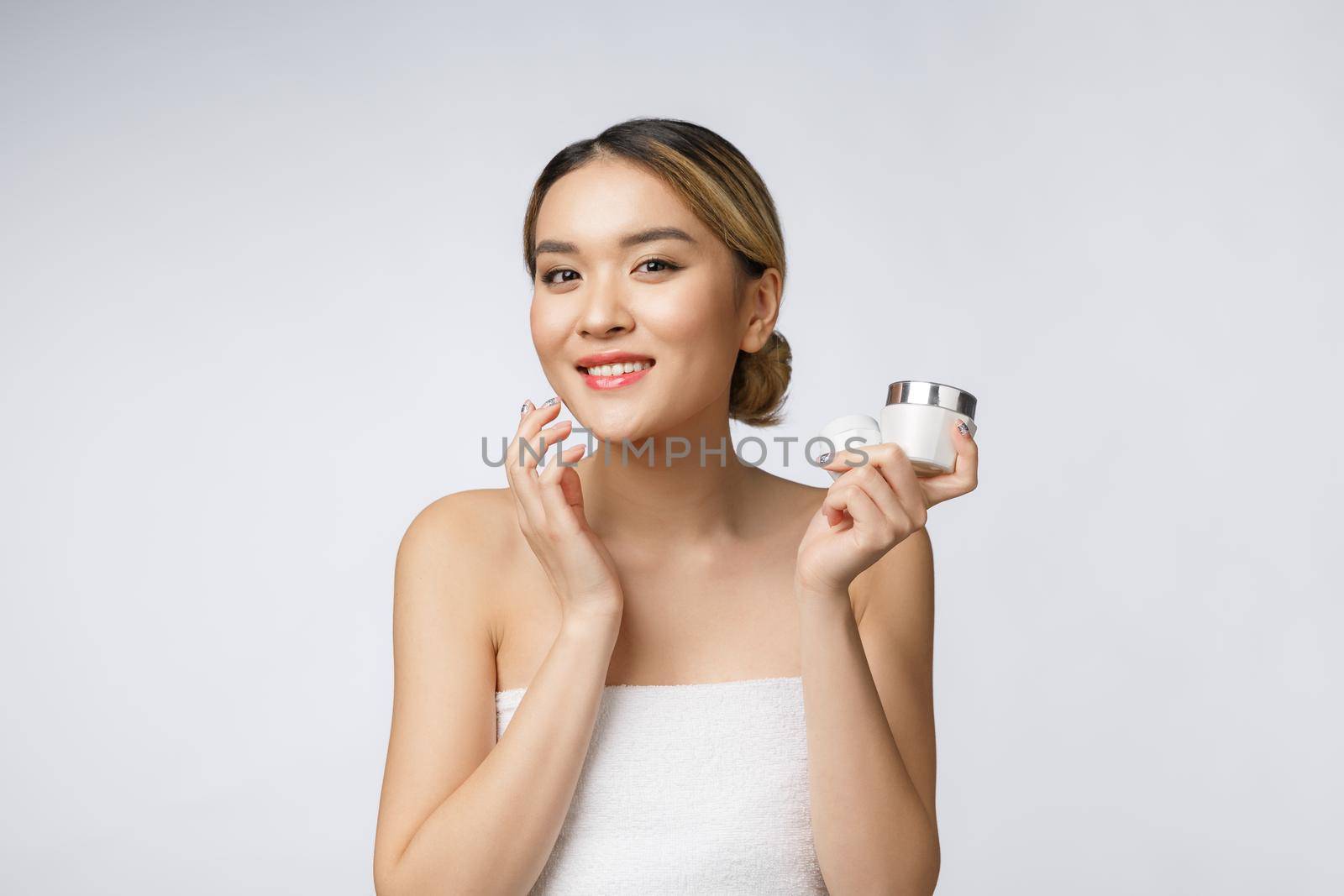 Asian woman applying cosmetic cream on skin on isolated white background by Benzoix
