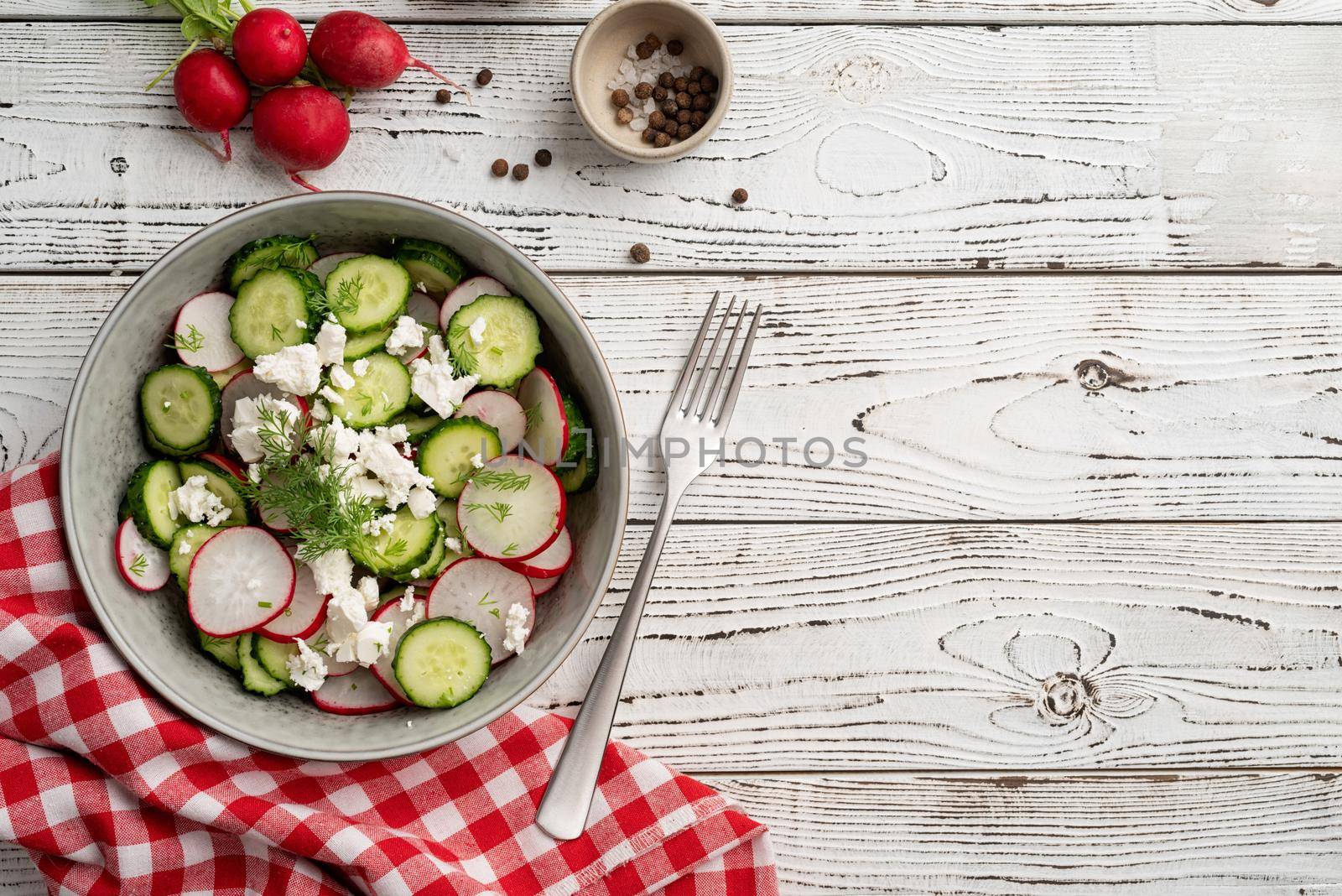 Bowl of healthy vegetarian salad with radish cucumber and fennel. top view on wooden background with copy space, summer food