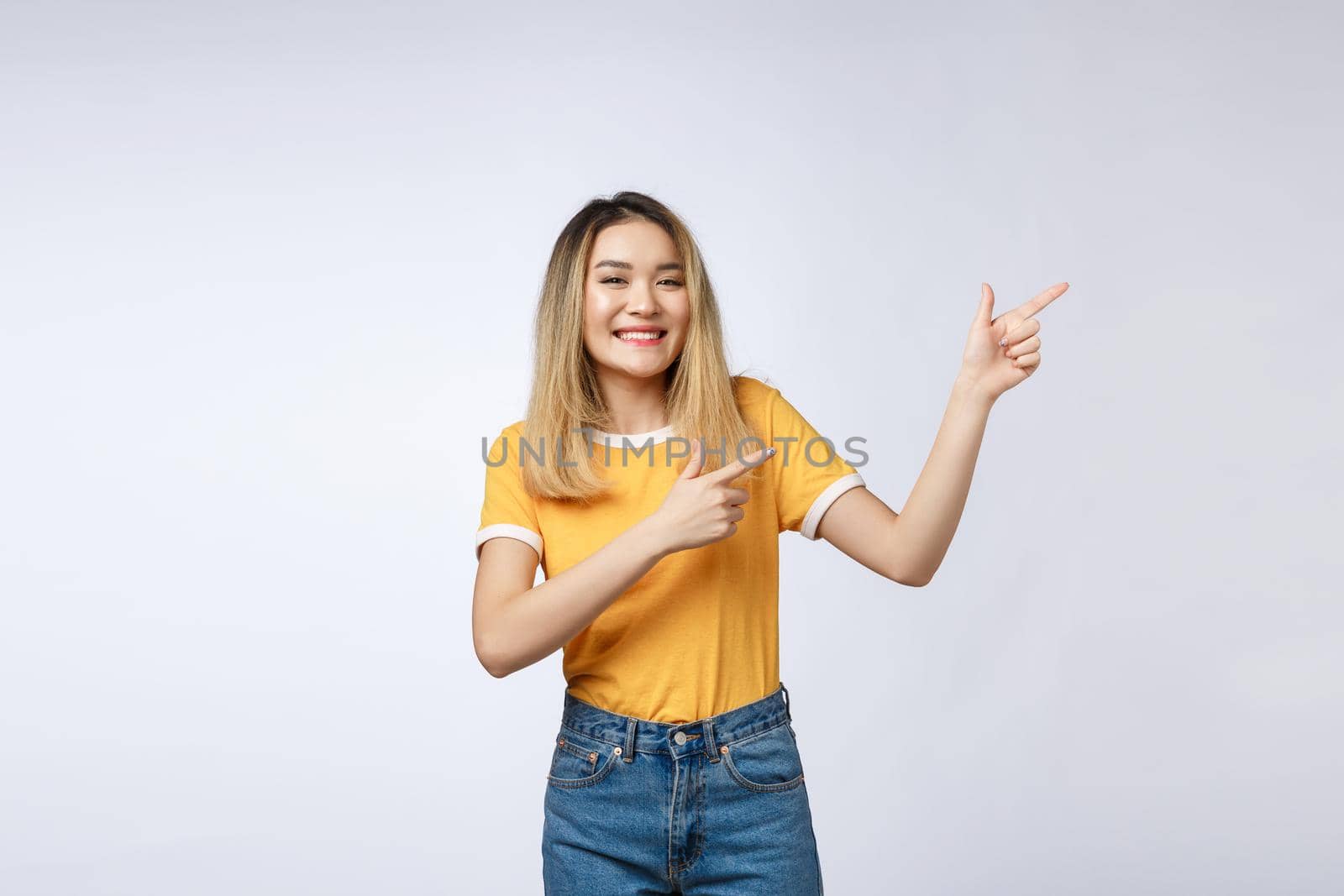 Beautiful young Asian woman pointing her finger up with cheerful expression, on white background. by Benzoix