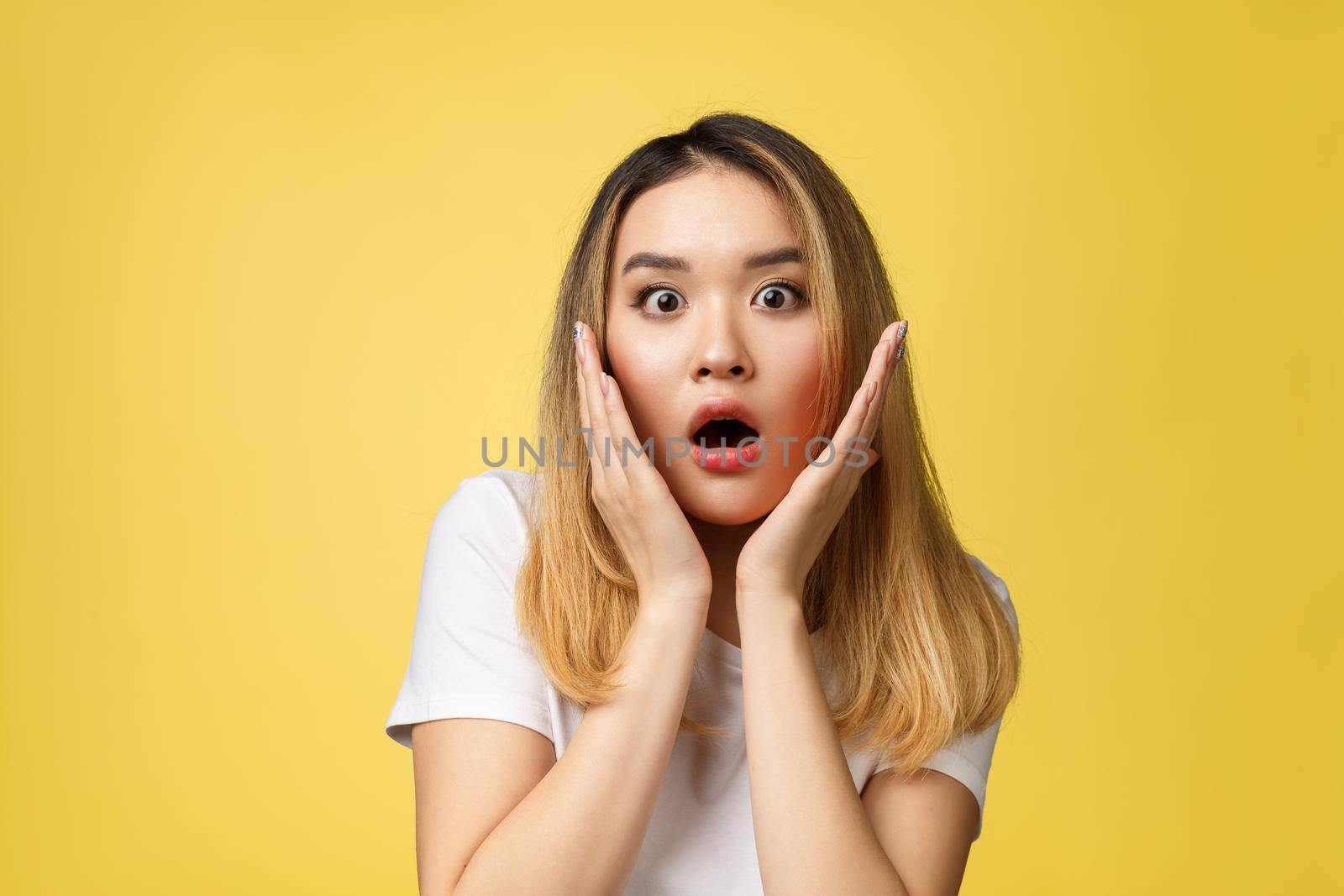 Surprised young asian woman face isolate over yellow background. by Benzoix