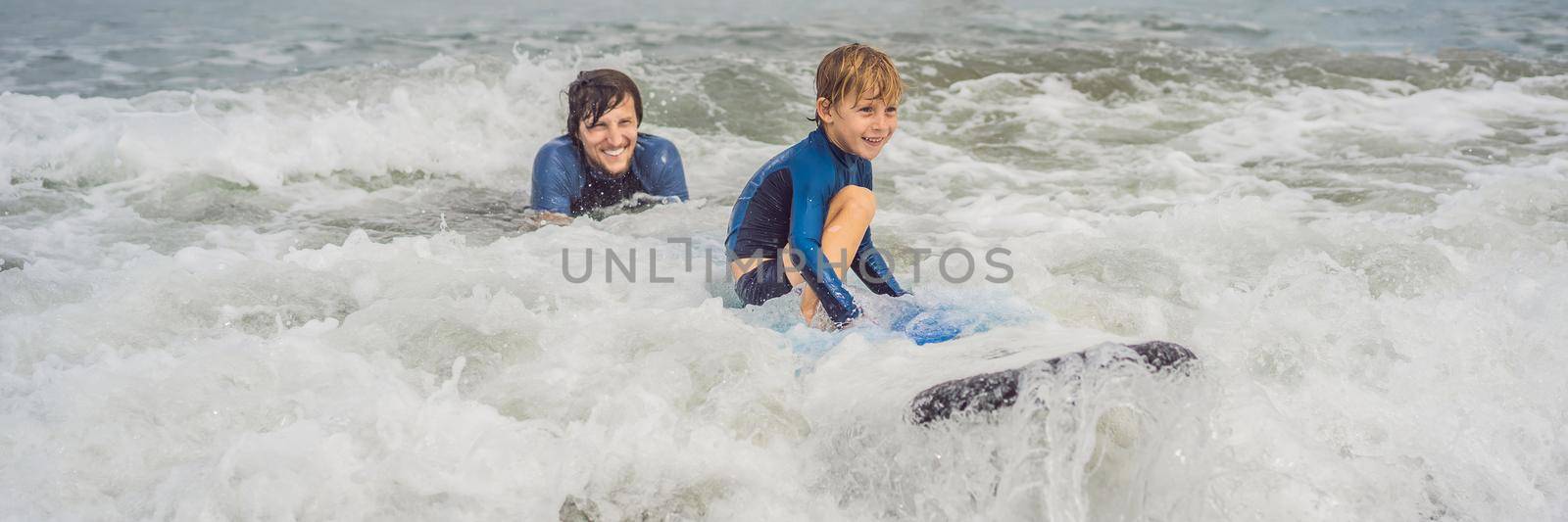 Father or instructor teaching his 5 year old son how to surf in the sea on vacation or holiday. Travel and sports with children concept. Surfing lesson for kids. BANNER, LONG FORMAT