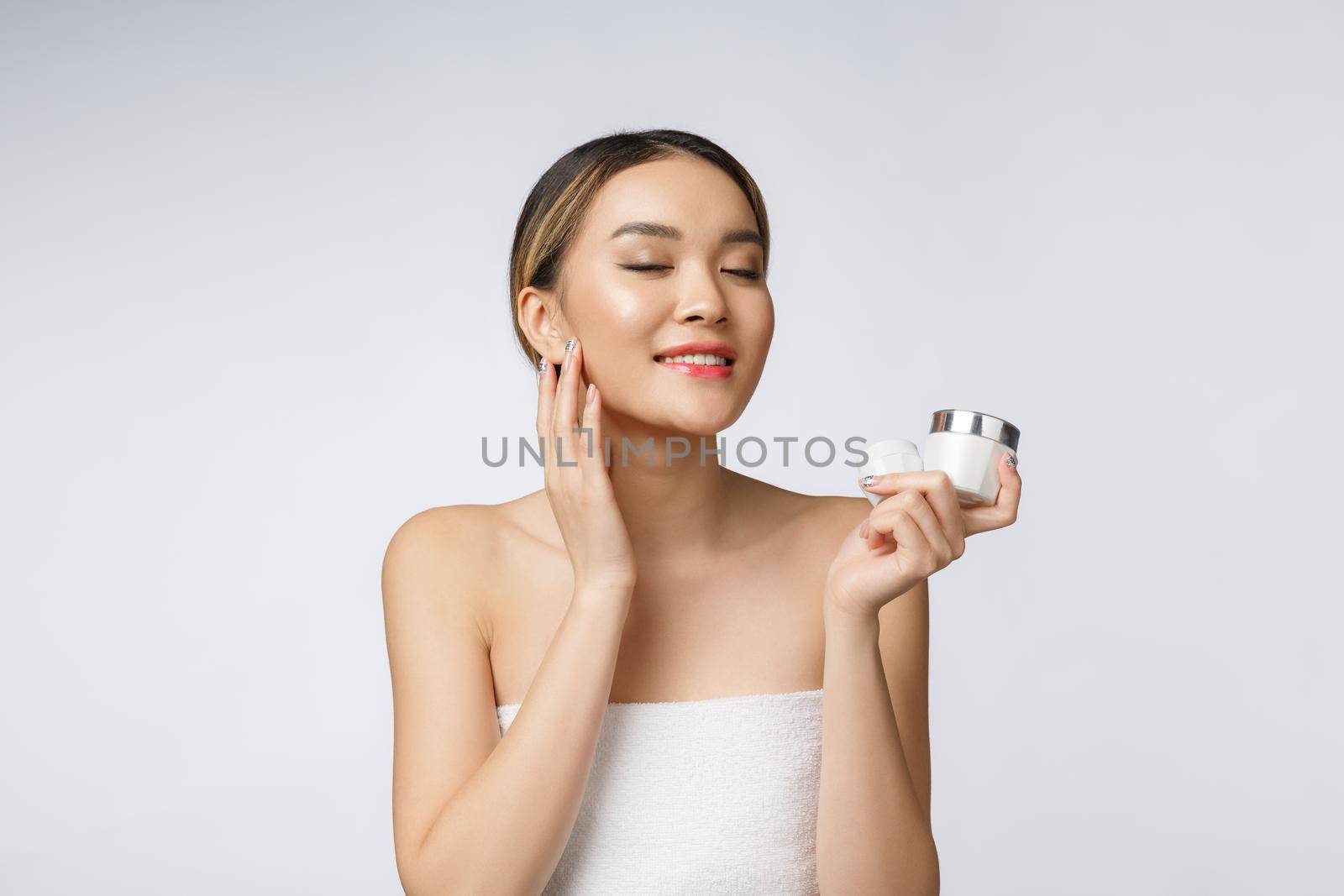 Asian woman applying cosmetic cream on skin on isolated white background by Benzoix