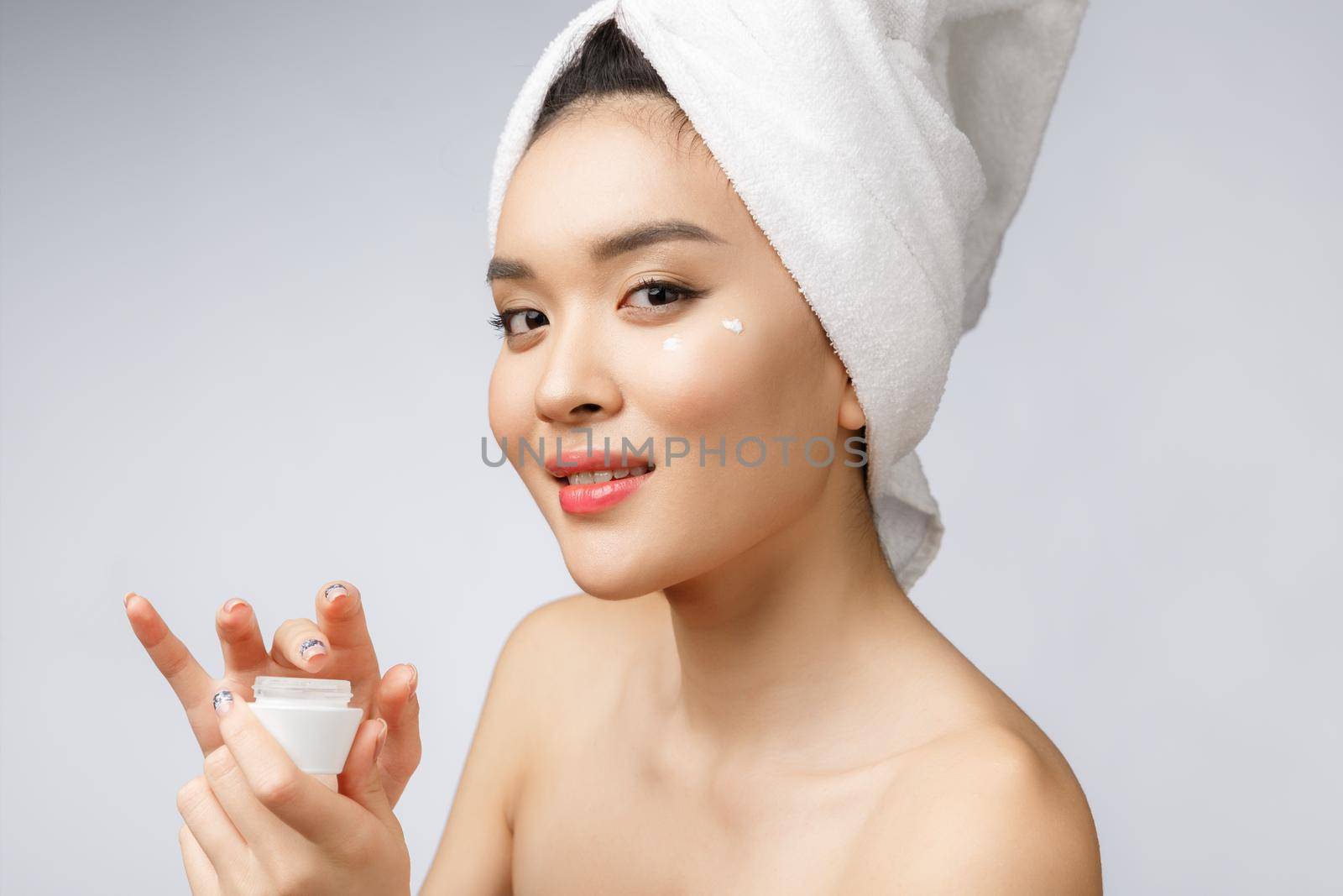 health and beauty concept - Attractive asian woman applying cream on her skin, isolated on white