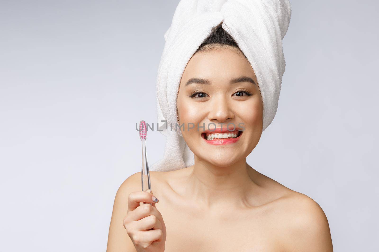 Beautiful young woman on white isolated background holds a toothbrush, Asian.