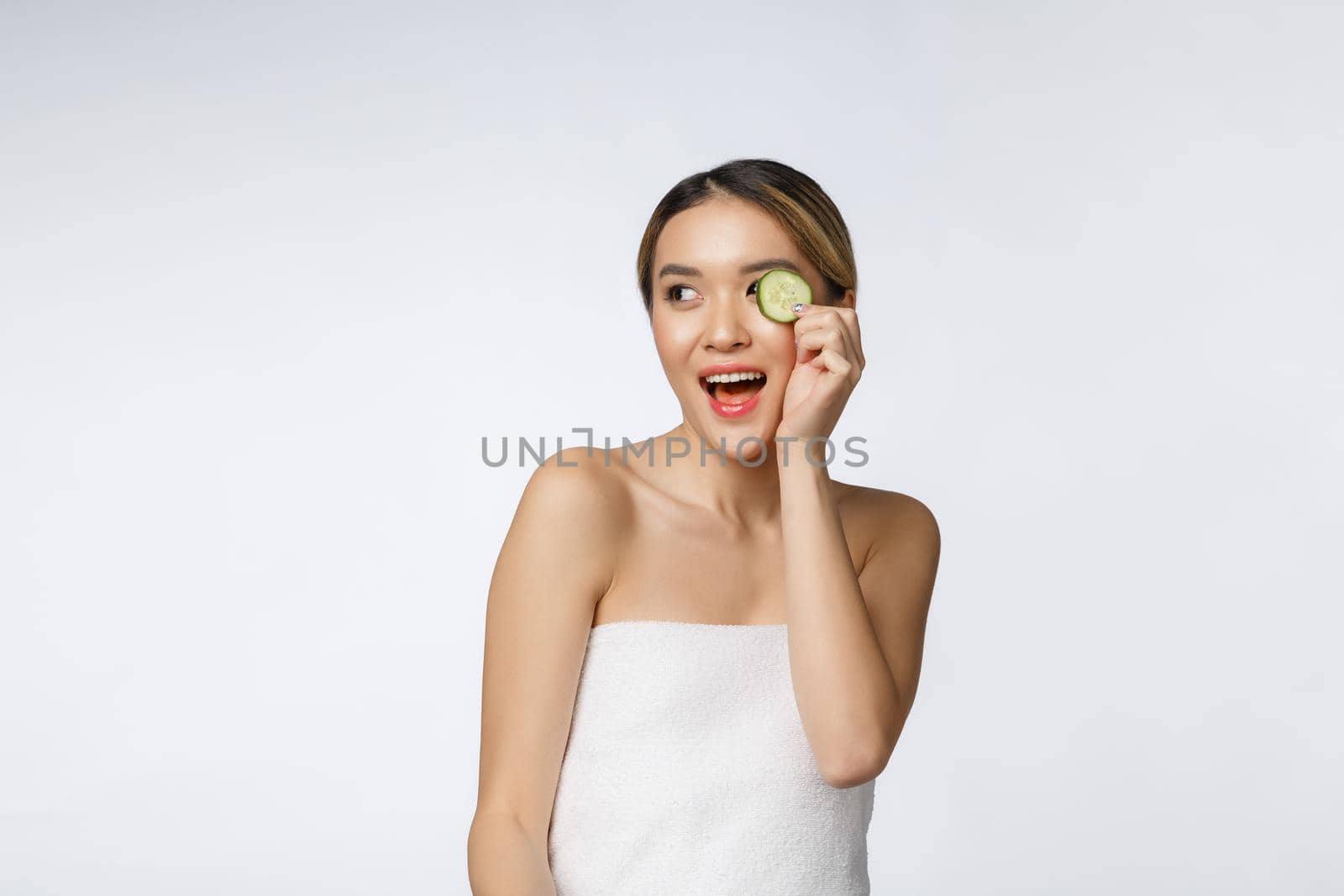 Young asian woman with cucumber slice in her hands isolated on white background