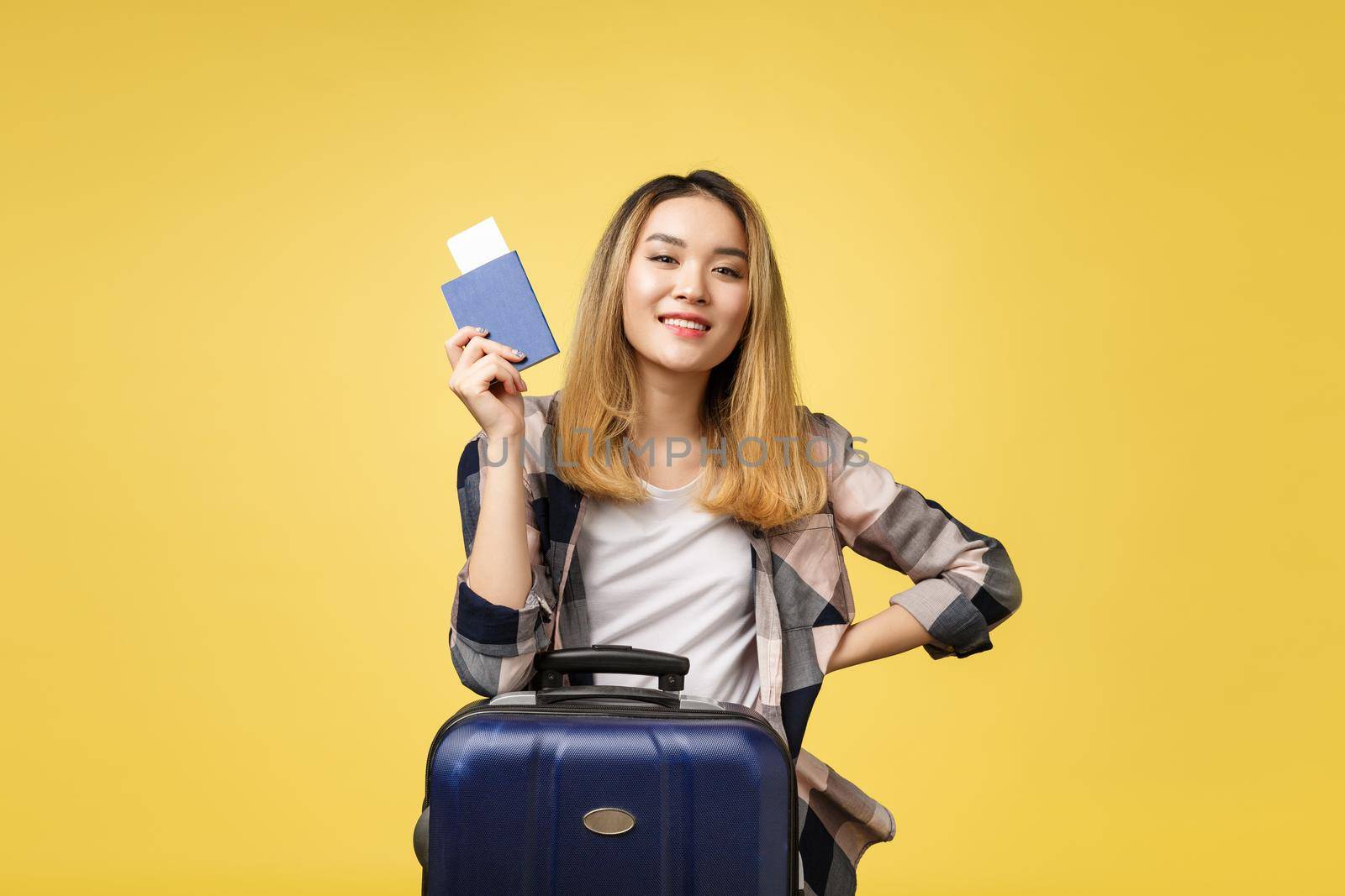Woman travel. Young beautiful asian woman traveler holding passport ,suitcase and air ticket standing over yellow