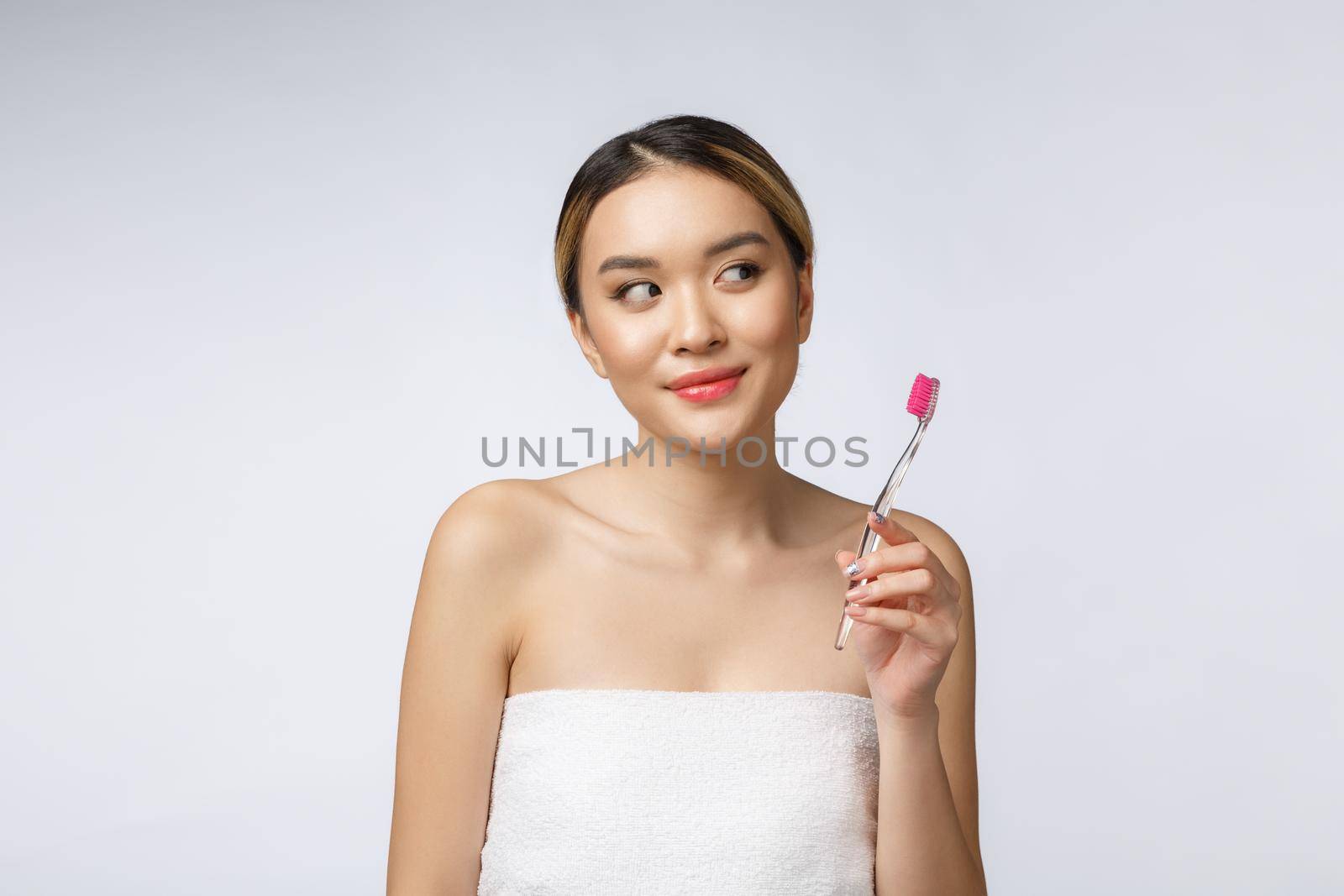 Beautiful young woman on white isolated background holds a toothbrush, Asian.