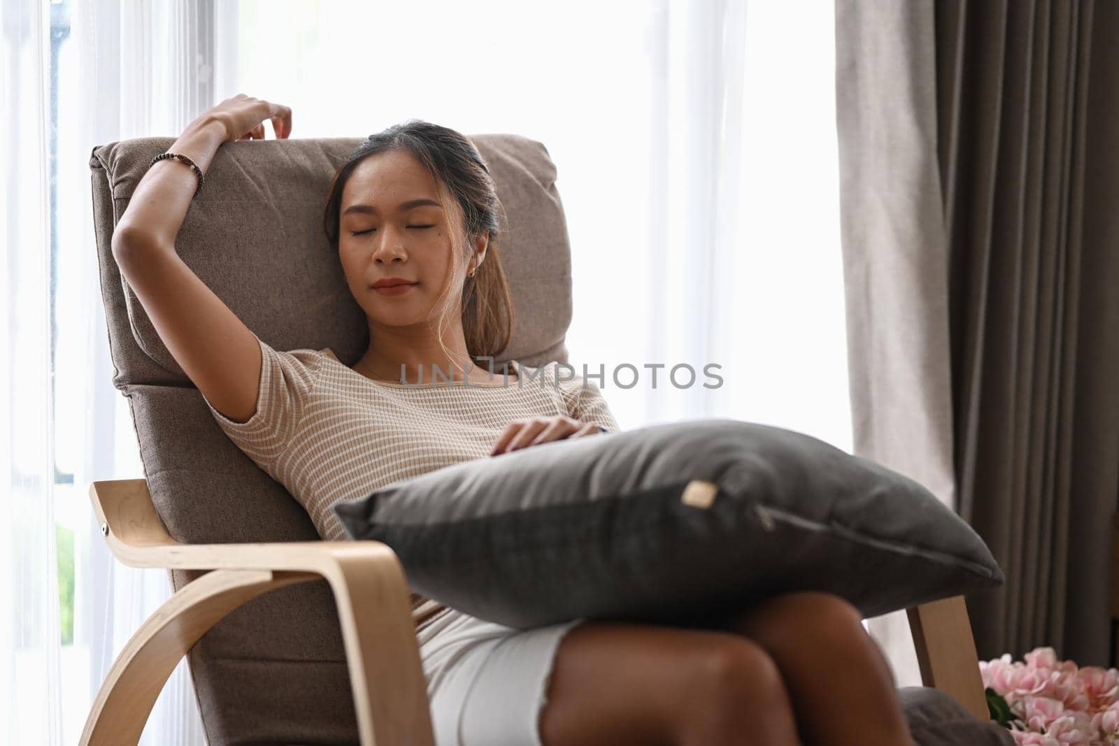Relaxed young woman in casual clothes resting on comfortable armchair at home.