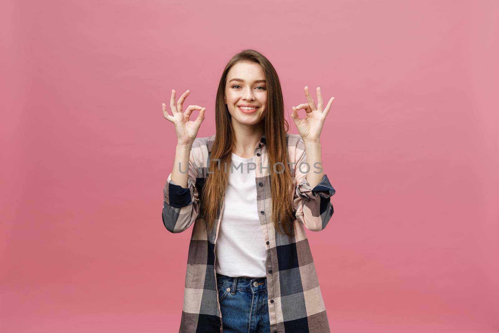 Attractive young adult woman showing ok sign. Expression emotion and feelings concept. Studio shot, isolated on pink background. by Benzoix