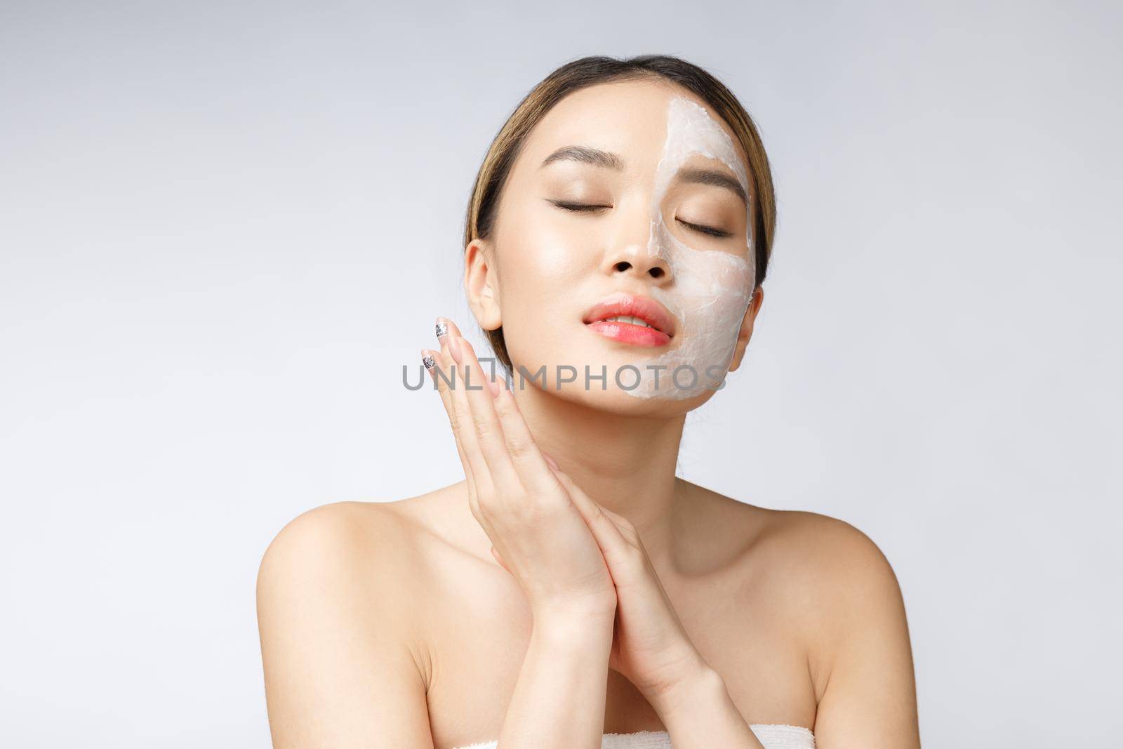 Charming pleasant woman applying cream on half face