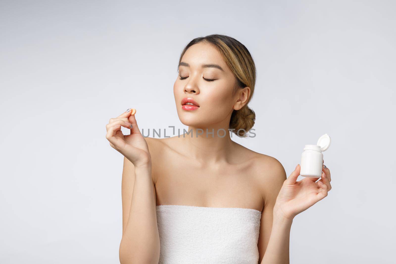 Healthy happy asian woman with pills in hand isolate over white background