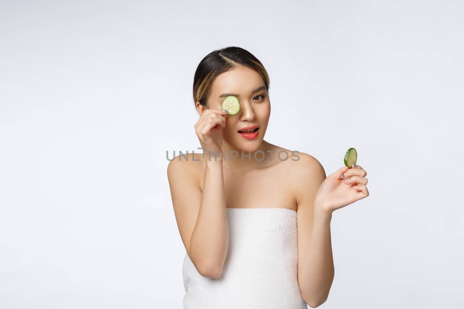 Young asian woman with cucumber slice in her hands isolated on white background