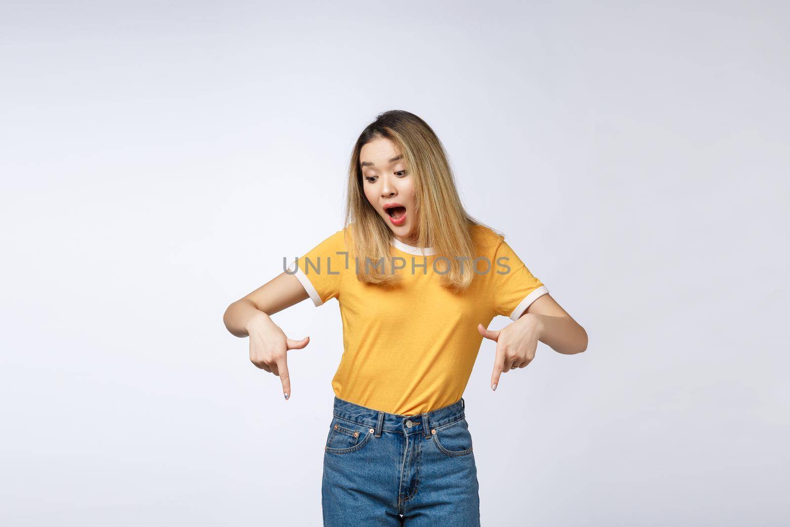 Smiling woman pointing finger on copy space. Isolated portrait on white