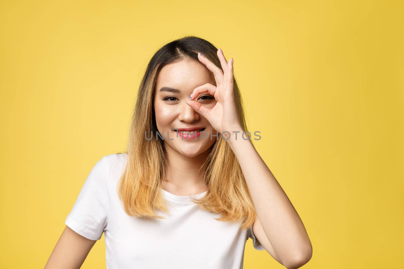 Asian young woman with ok sign gesture isolate over yellow background