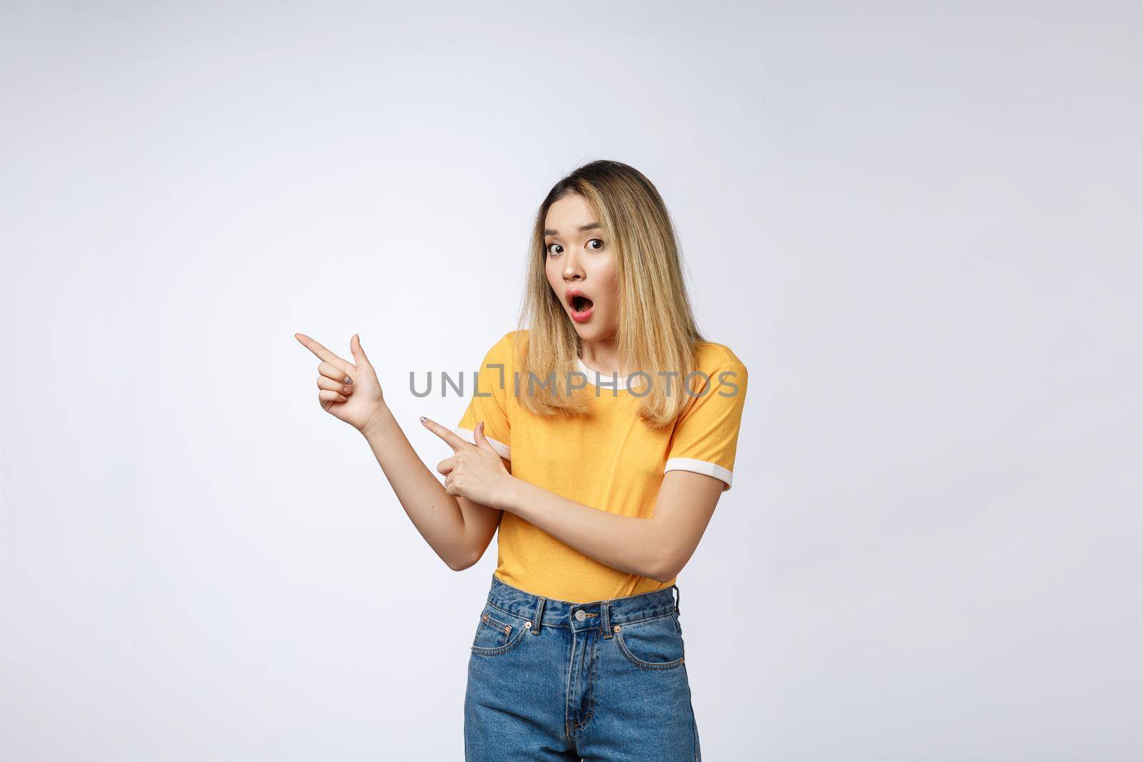 Smiling woman pointing finger on copy space. Isolated portrait on white