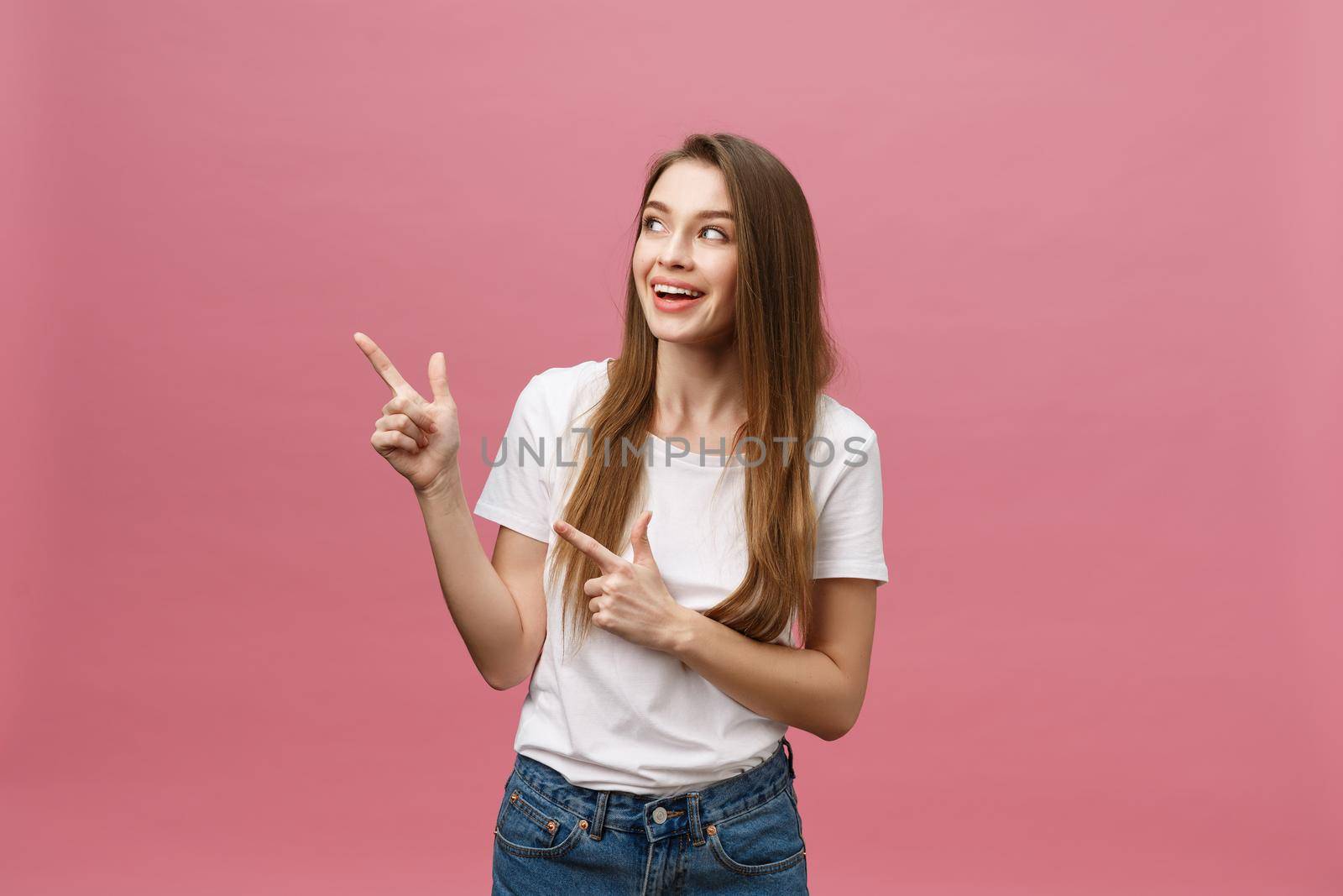 Woman pointing finger at camera and toothy smiling. Expression emotion and feelings concept. Studio shot, isolated on pink background.