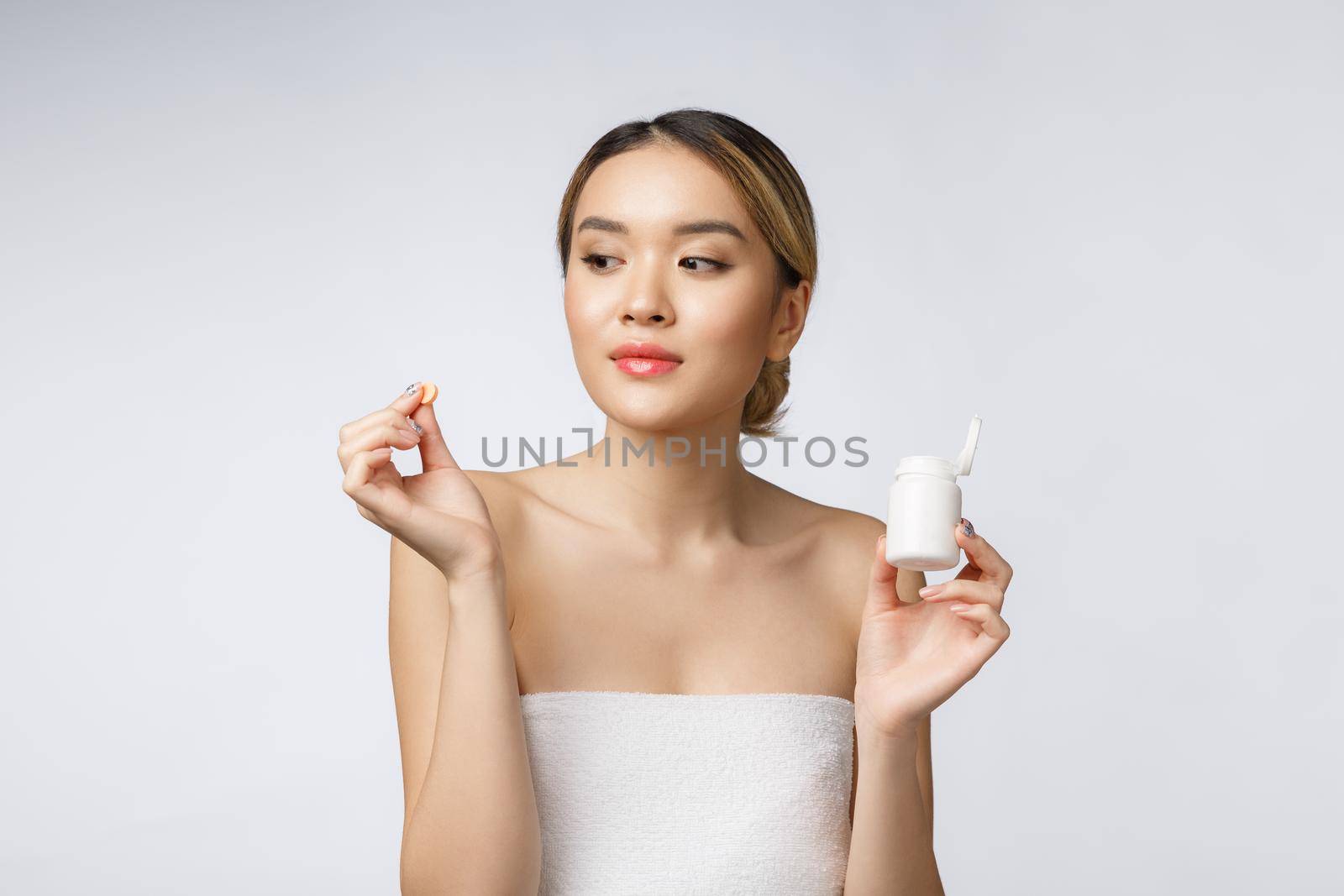 Healthy happy asian woman with pills in hand isolate over white background