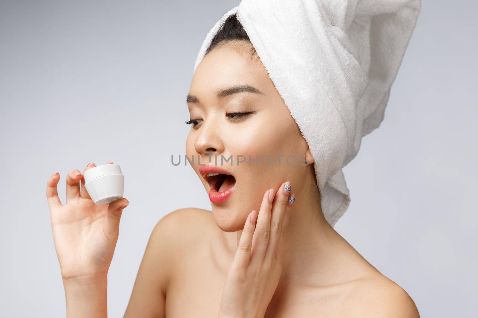 health and beauty concept - Attractive asian woman applying cream on her skin, isolated on white