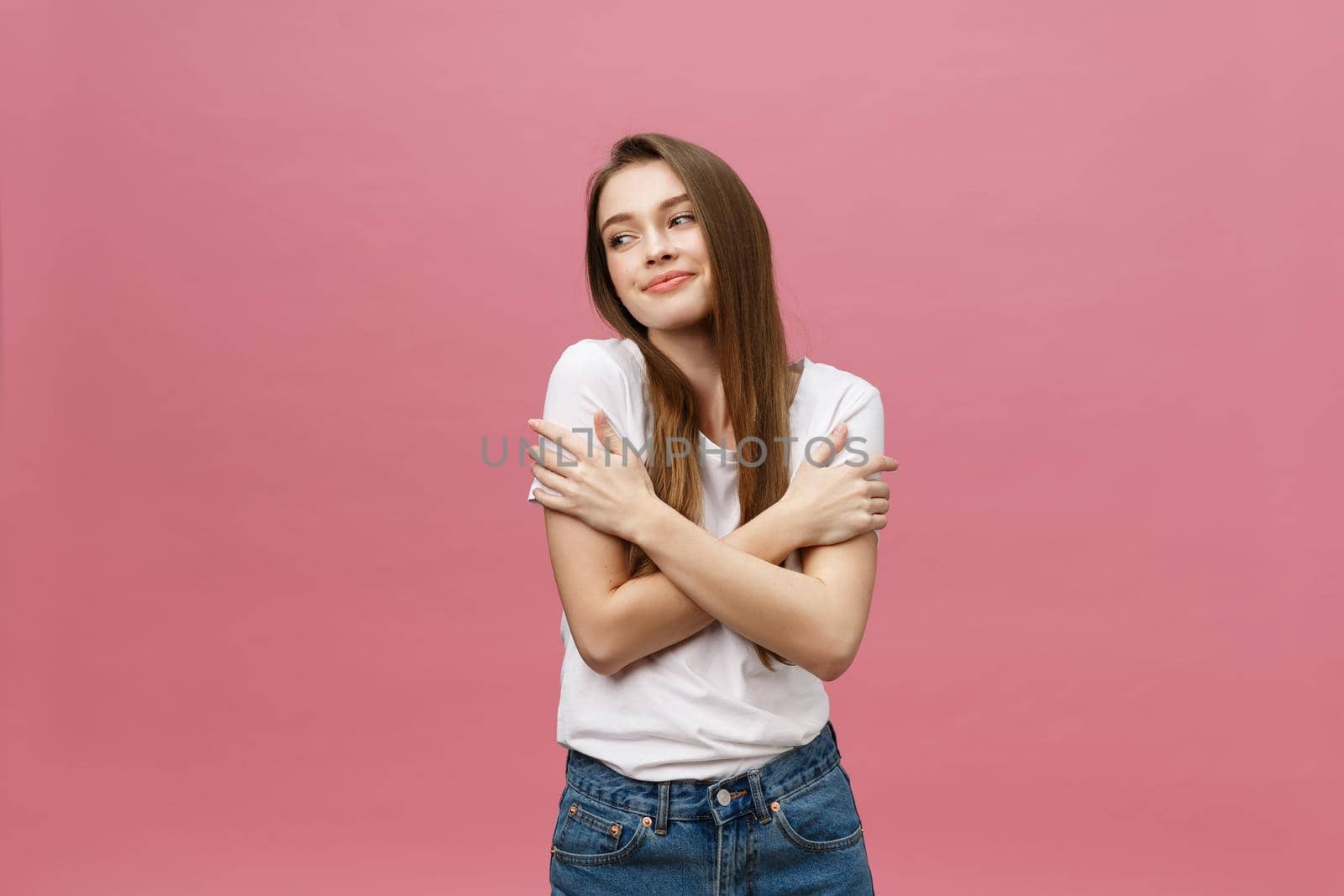 Portrait of a happy woman standing with arms folded isolated on a pink background.