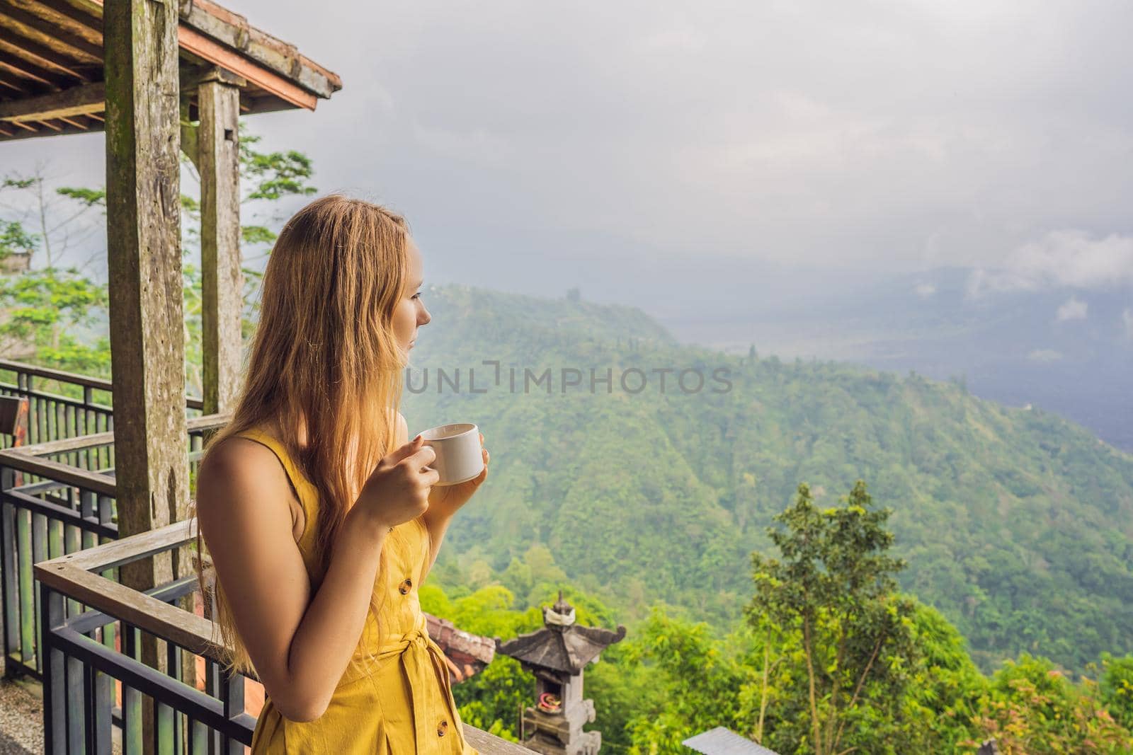 Young woman drinks coffee in a cafe in the mountains.