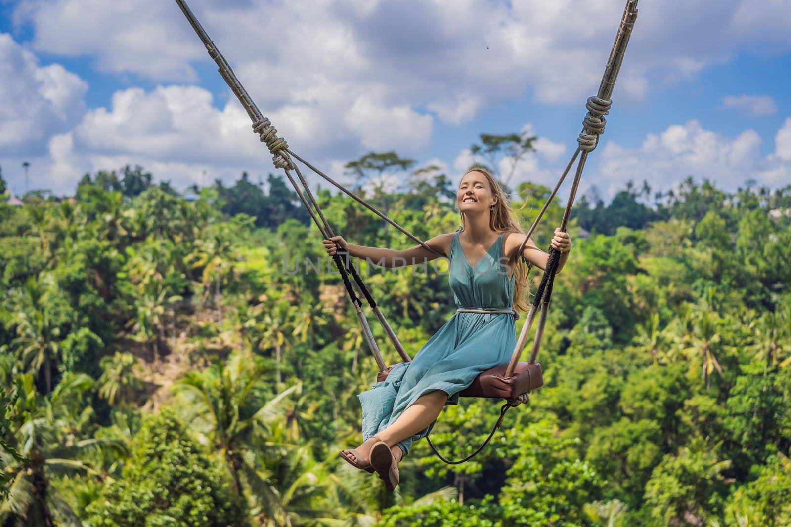 Young woman swinging in the jungle rainforest of Bali island, Indonesia. Swing in the tropics. Swings - trend of Bali.