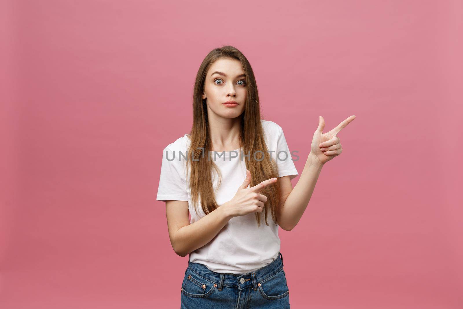 Woman pointing finger at camera and toothy smiling. Expression emotion and feelings concept. Studio shot, isolated on pink background.