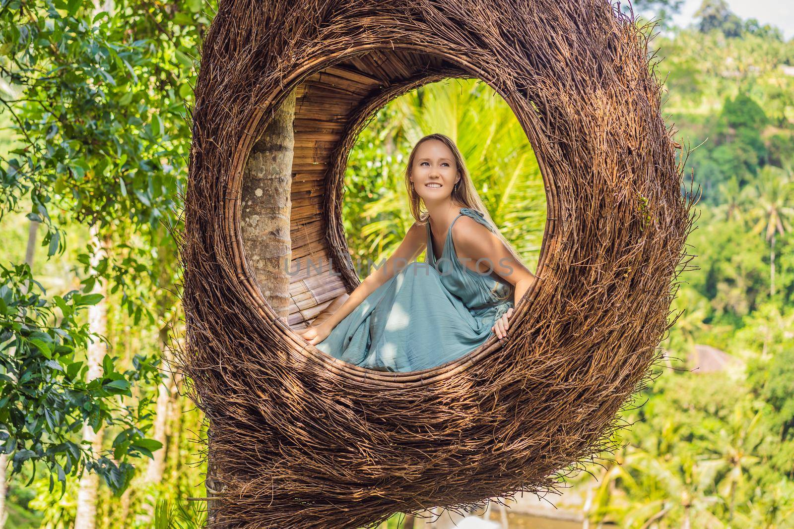 Bali trend, straw nests everywhere. Young tourist enjoying her travel around Bali island, Indonesia. Making a stop on a beautiful hill. Photo in a straw nest, natural environment. Lifestyle.