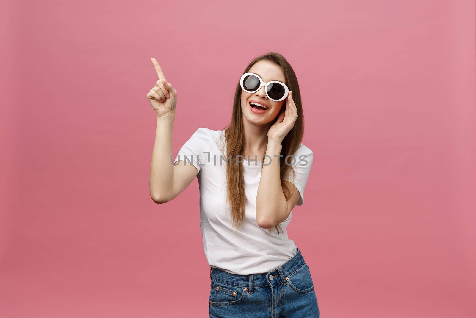 Cute young woman points a finger away isolate over pink background. Copy Space