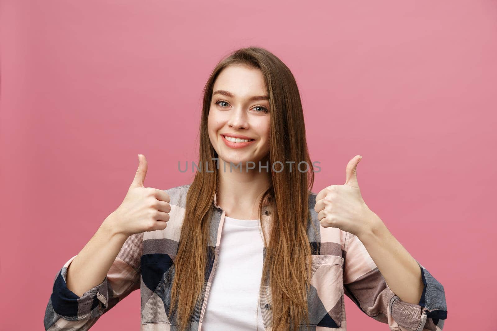 Close-up shot of smiling pretty girl showing thumb up gesture. Female isolated over pink background in the studio. by Benzoix