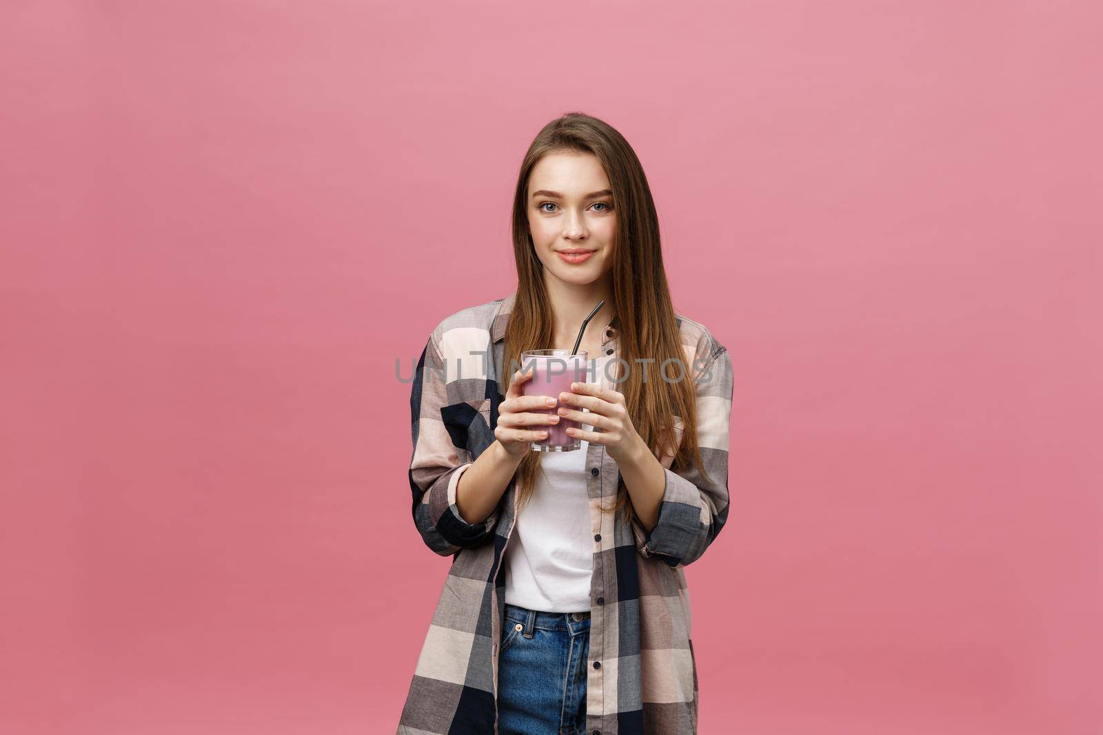 Young woman drinking juice smoothie with straw. Isolated studio portrait