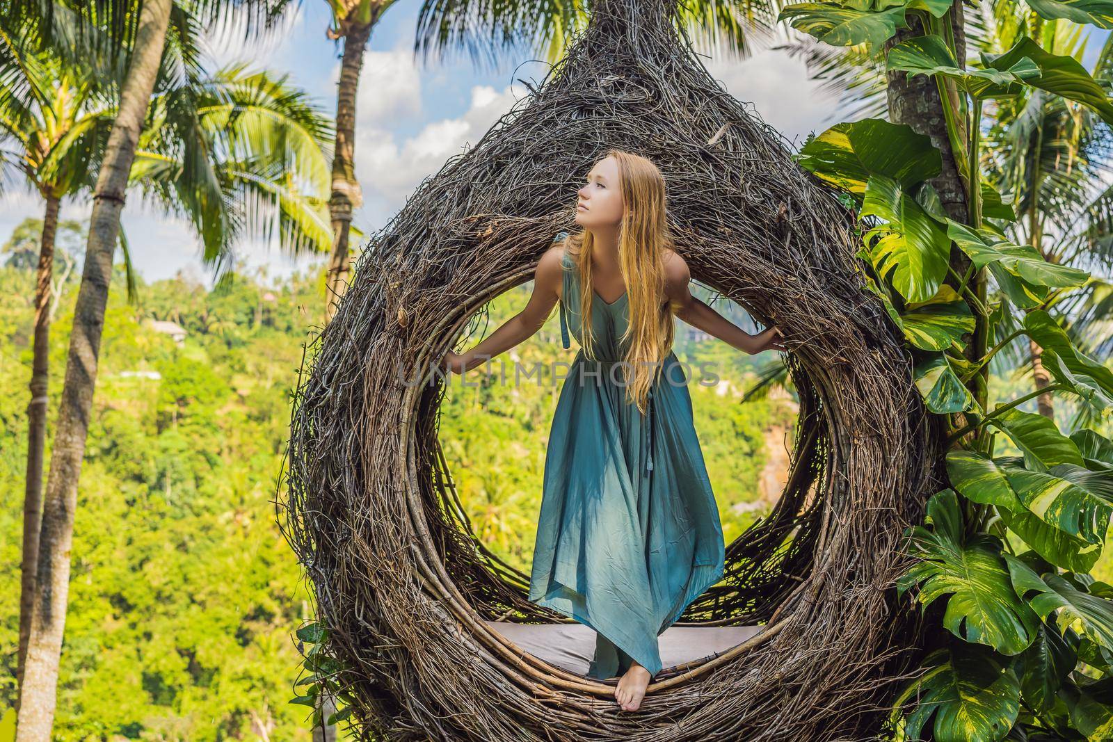 Bali trend, straw nests everywhere. Young tourist enjoying her travel around Bali island, Indonesia. Making a stop on a beautiful hill. Photo in a straw nest, natural environment. Lifestyle.