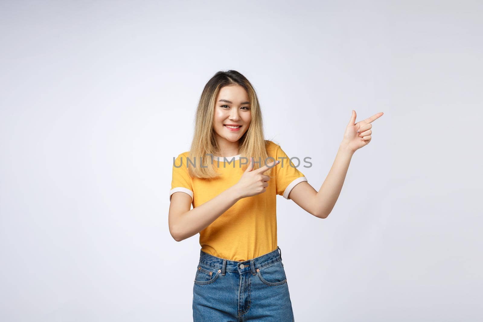 Beautiful young Asian woman pointing her finger up with cheerful expression, on white background