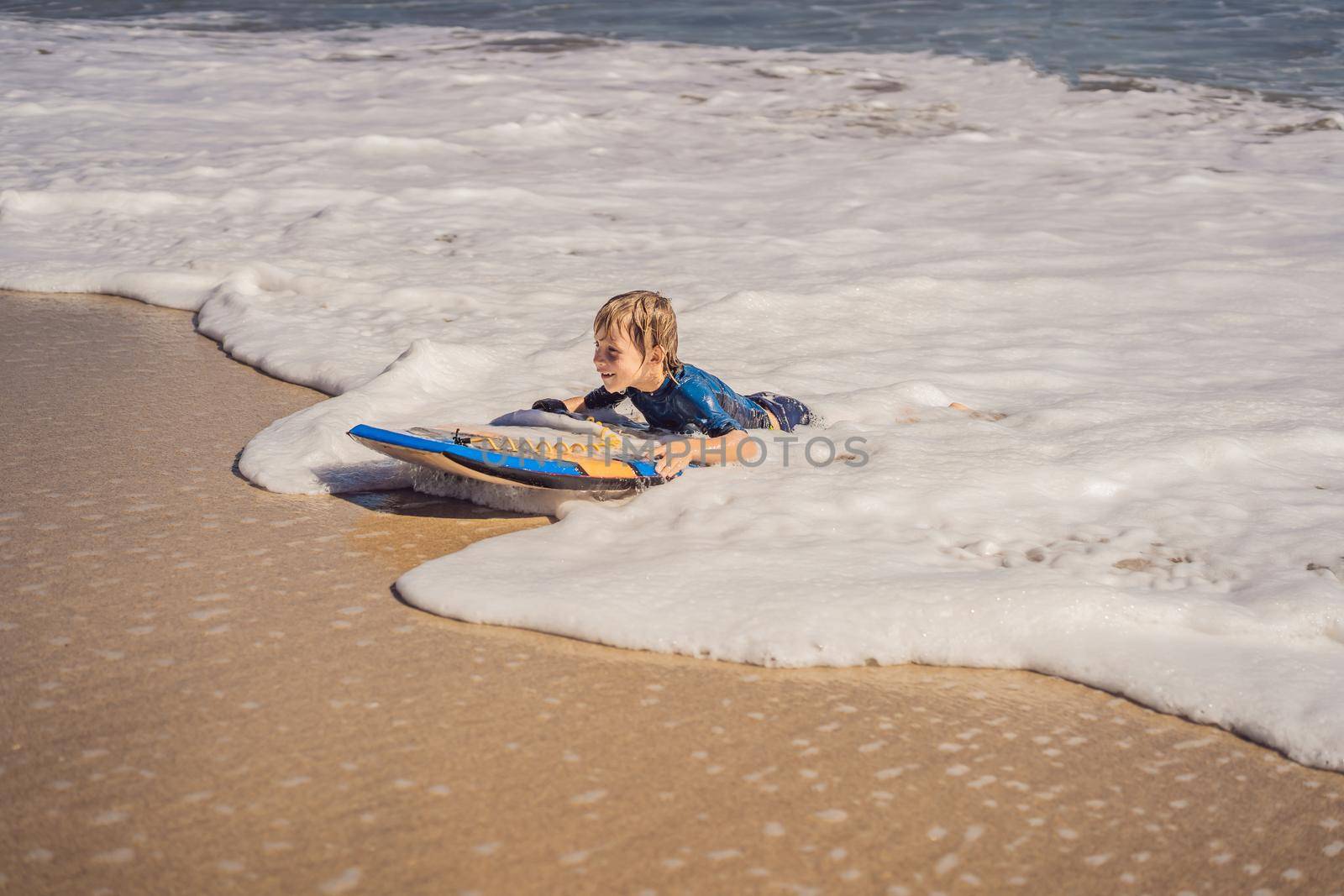 Happy Young boy having fun at the beach on vacation, with Boogie board.