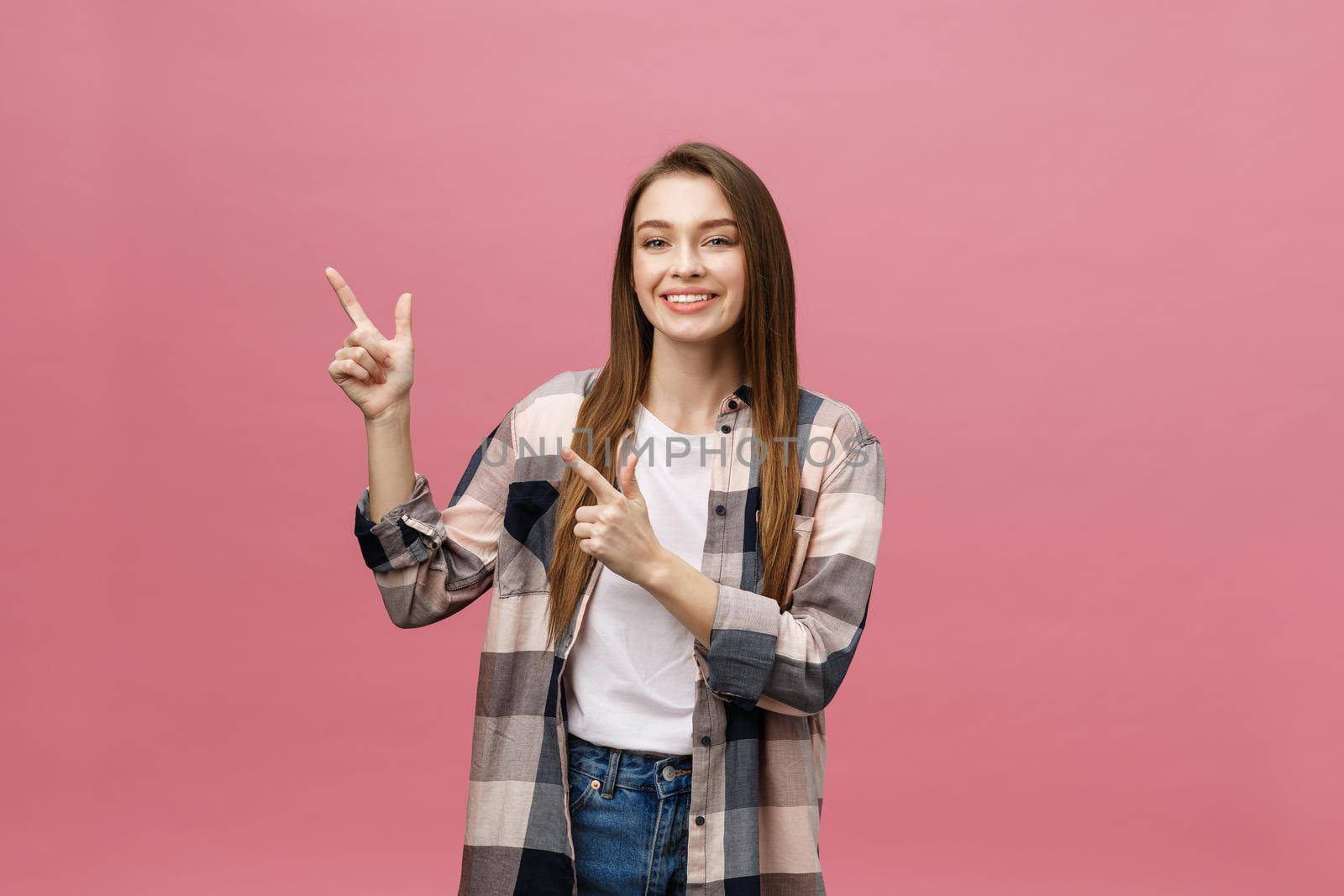 Cute young woman points a finger away isolate over pink background. Copy Space