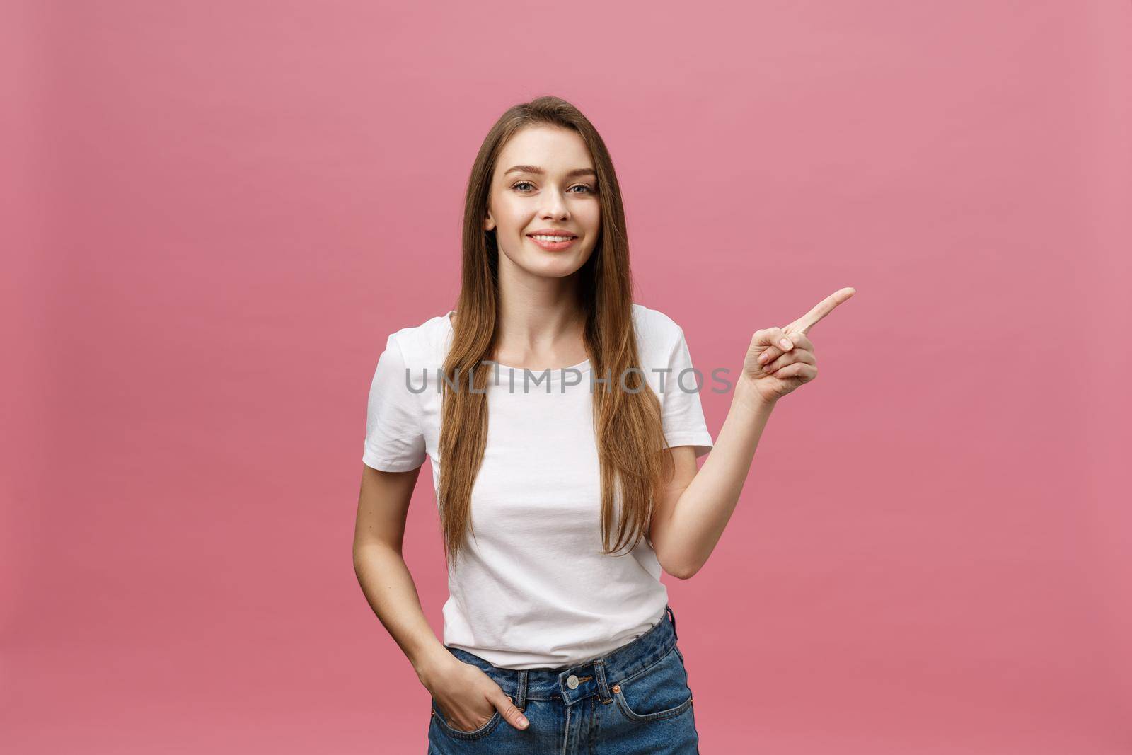 Photo of happy young woman standing and poiting finger isolated over pink background