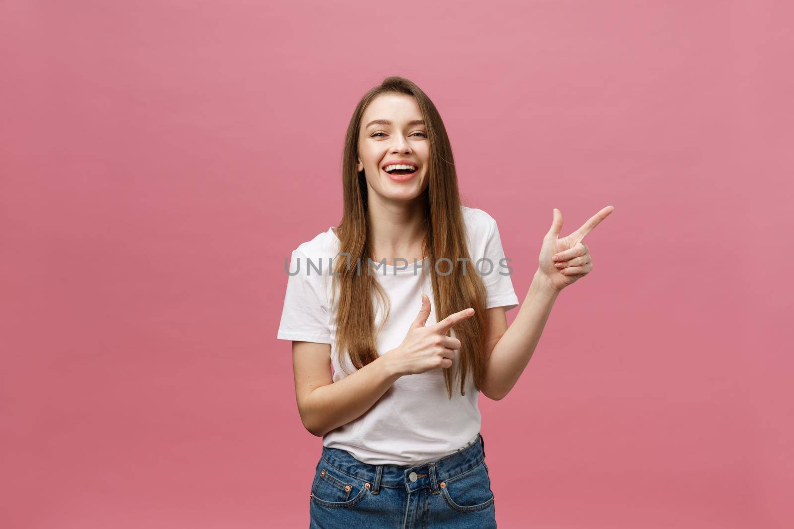 Woman pointing finger at camera and toothy smiling. Expression emotion and feelings concept. Studio shot, isolated on pink background by Benzoix