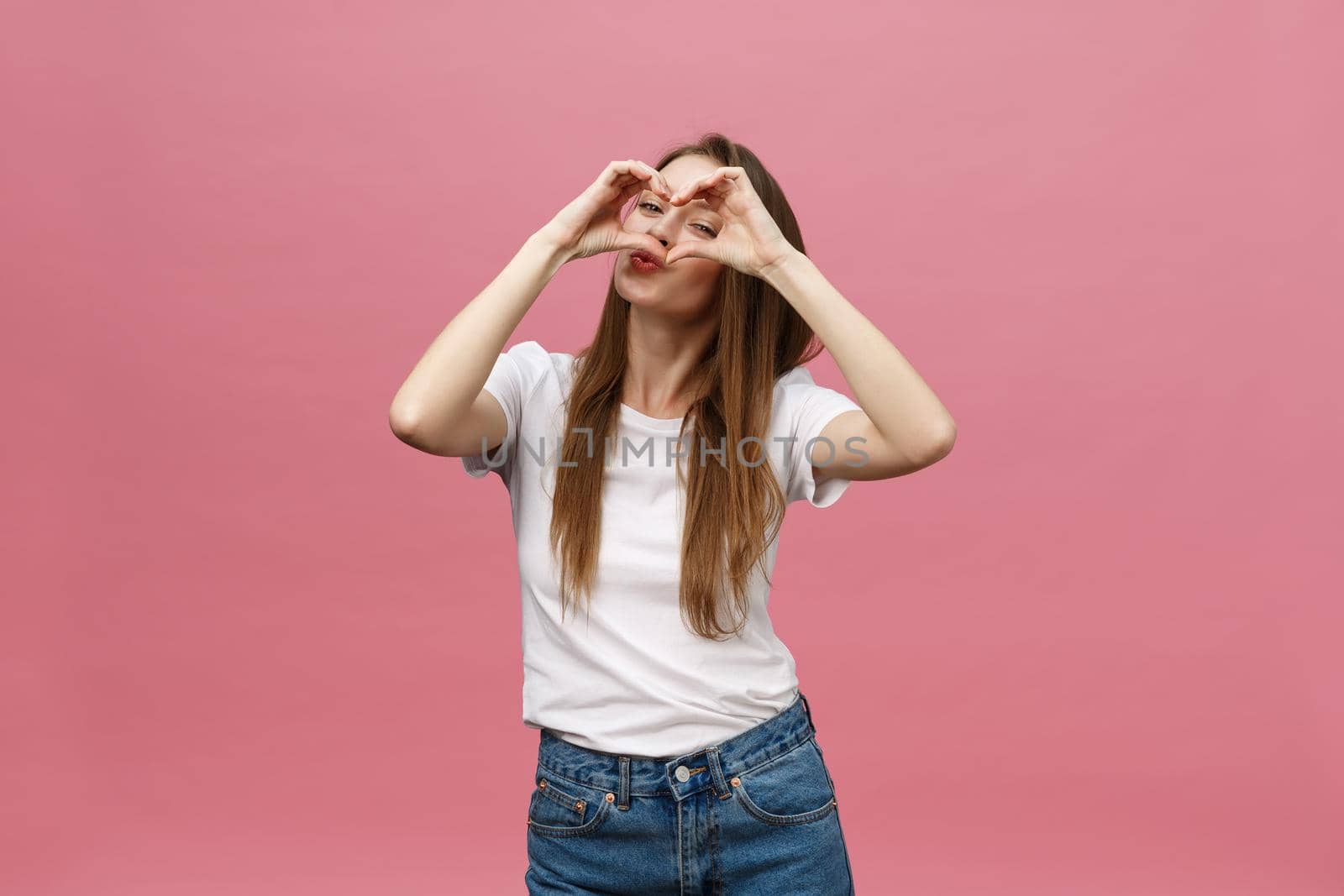 Lifestyle Concept: Beautiful attractive woman in white shirt making a heart symbol with her hands.