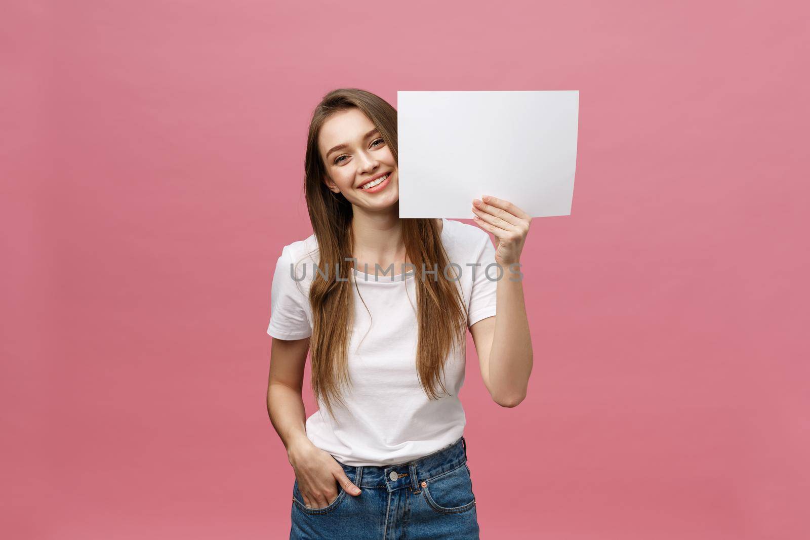 Close up portrait of positive laughing woman smiling and holding white big mockup poster isolated on pink background by Benzoix