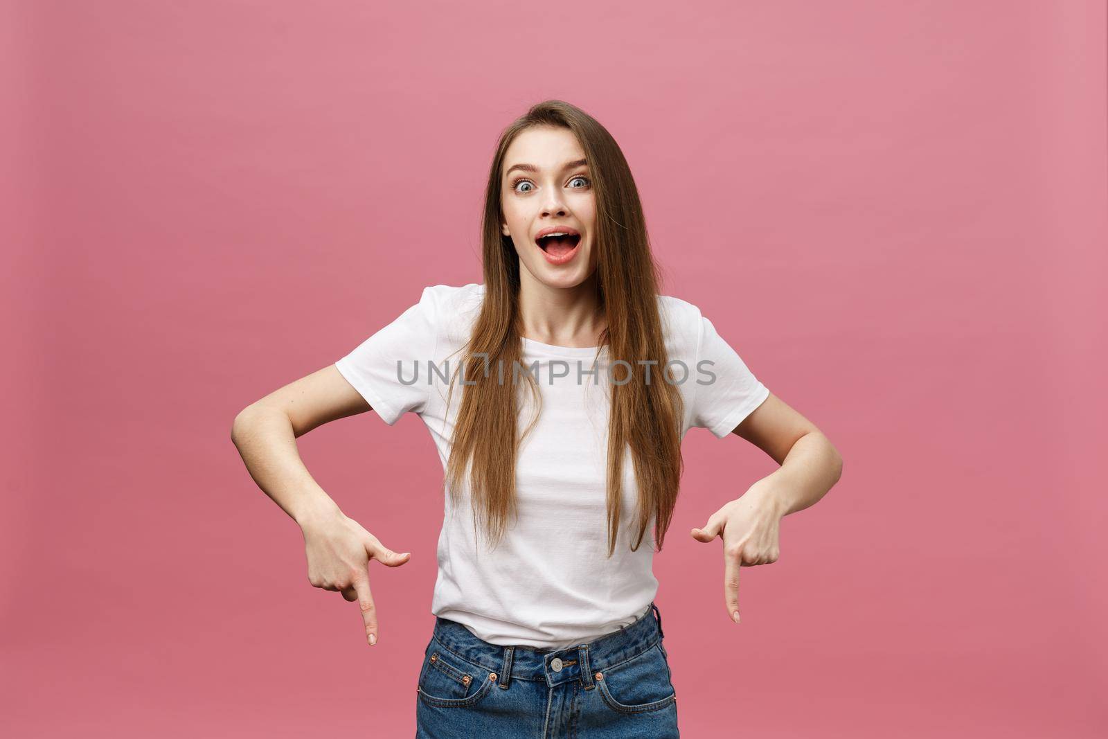 Woman pointing finger at camera and toothy smiling. Expression emotion and feelings concept. Studio shot, isolated on pink background.