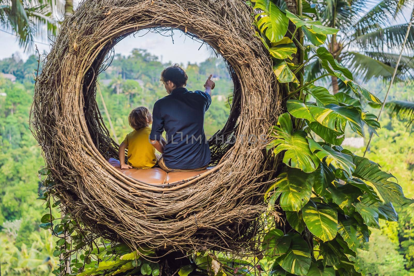 Bali trend, straw nests everywhere. Child friendly place. Happy family enjoying their travel around Bali island, Indonesia. Making a stop on a beautiful hill. Photo in a straw nest, natural environment. Lifestyle. Traveling with kids concept. What to do with children.