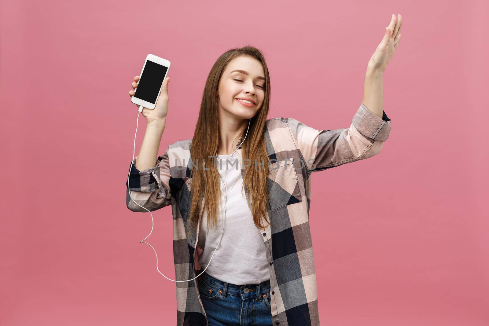 Lifestyle Concept. Young woman using phone for listening to music on pink background by Benzoix