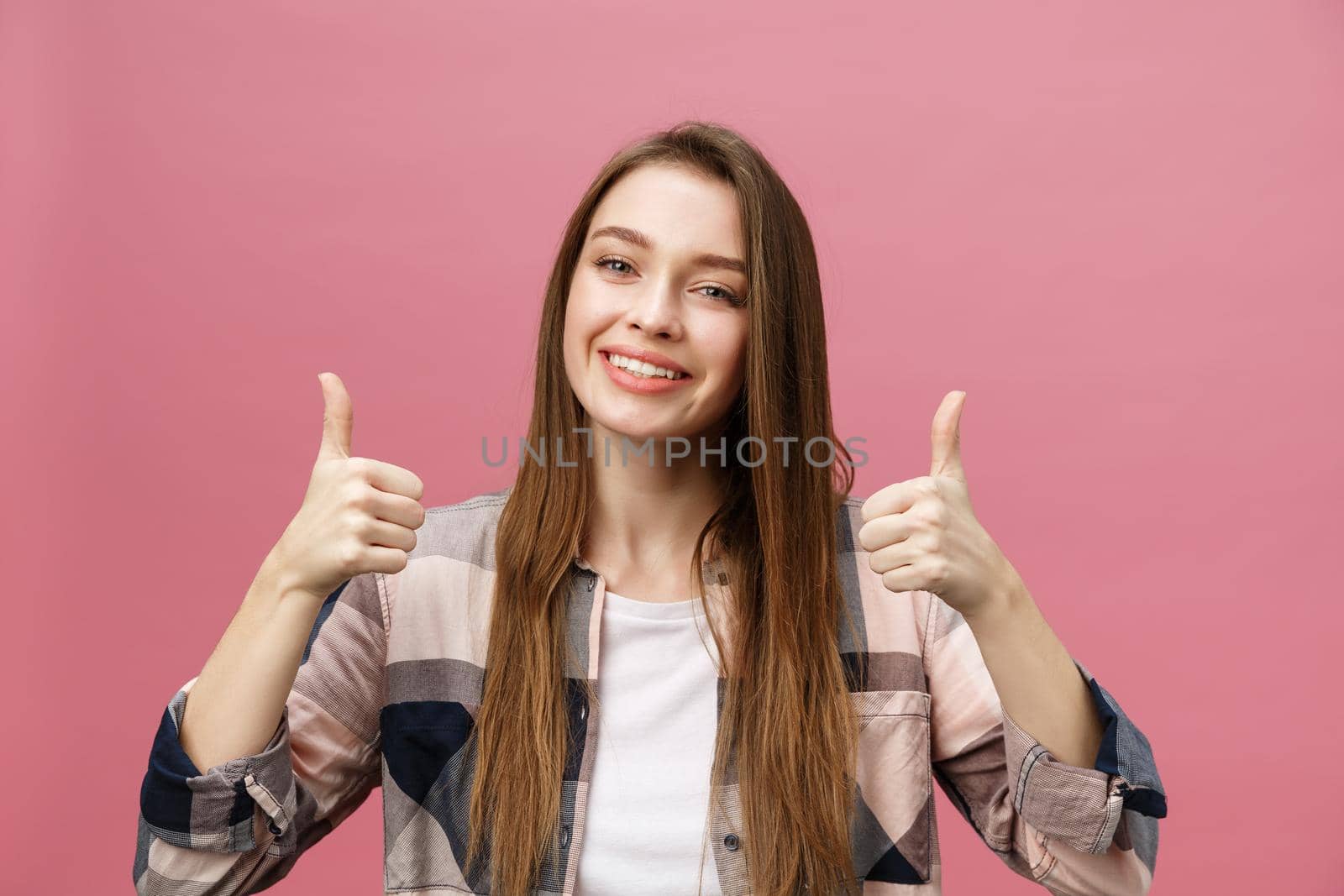 Close-up shot of smiling pretty girl showing thumb up gesture. Female isolated over pink background in the studio. by Benzoix