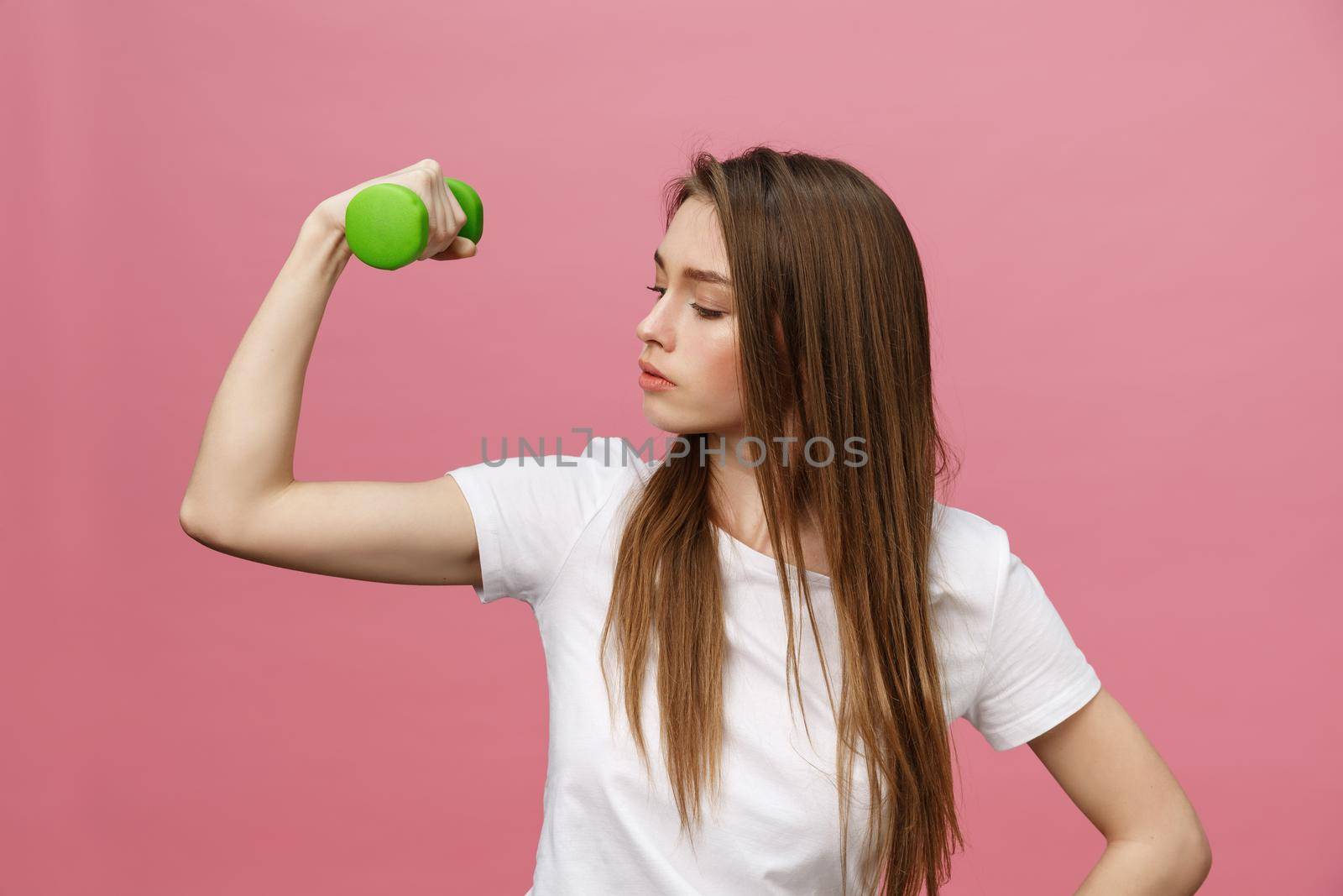Fitness, young woman with dumbbells at studio background. Pretty girl isolate over pink by Benzoix