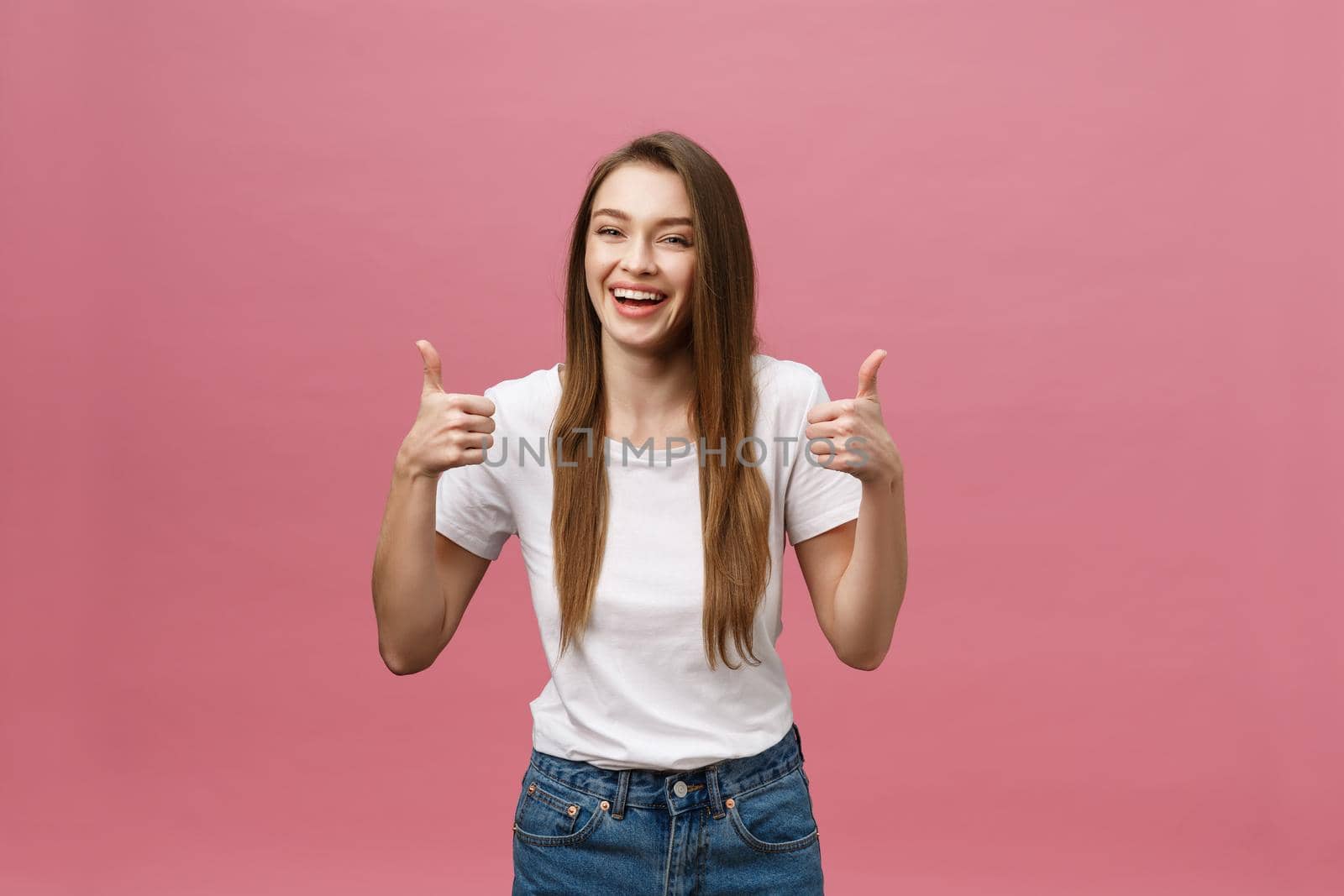 Happy young woman giving thumbs up on pink background. by Benzoix